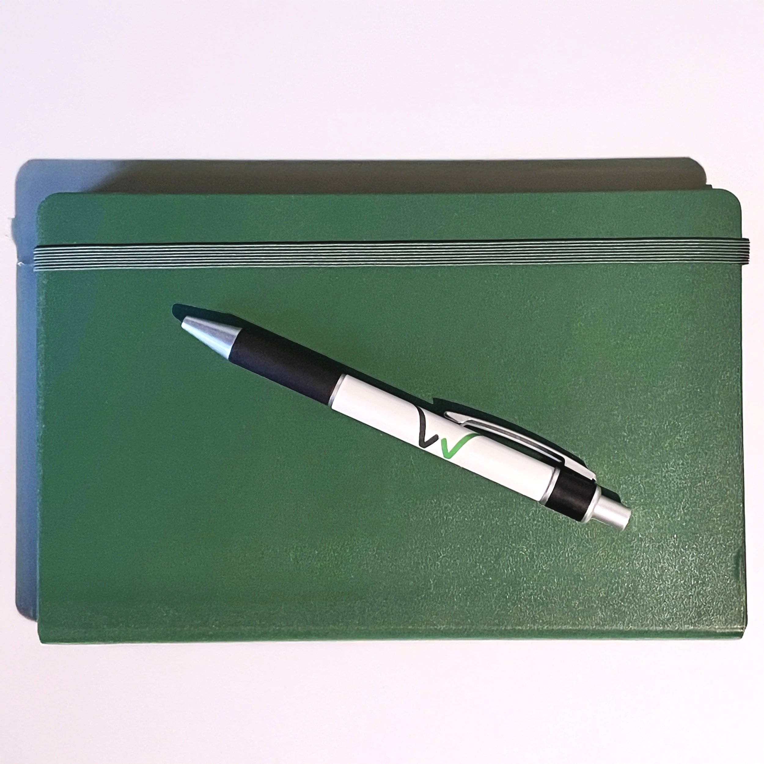 Two green notebooks stacked with a black and white pen resting on top, on a white background.