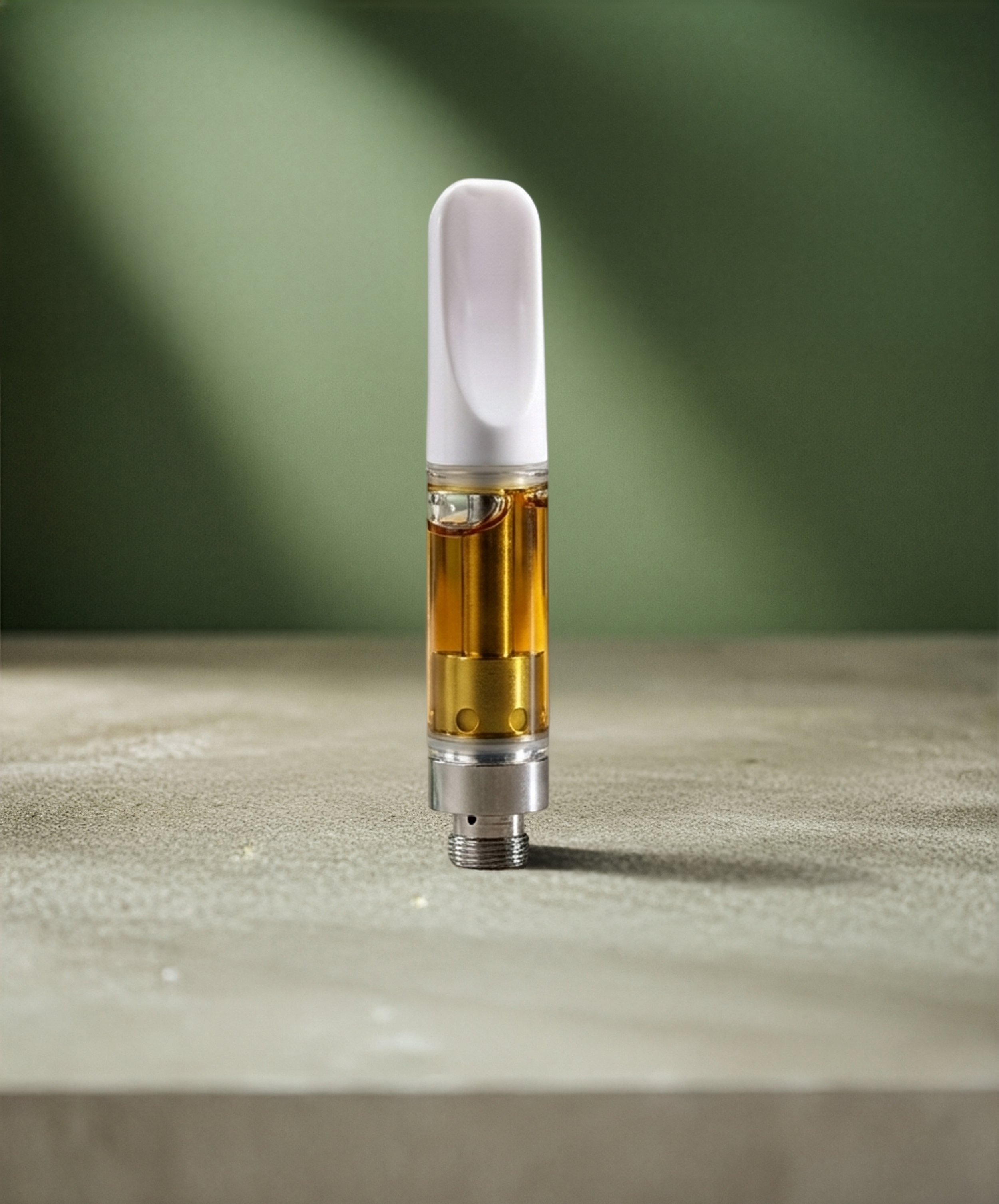 A vape pen filled with amber-colored liquid standing upright on a flat surface with a blurred green background.