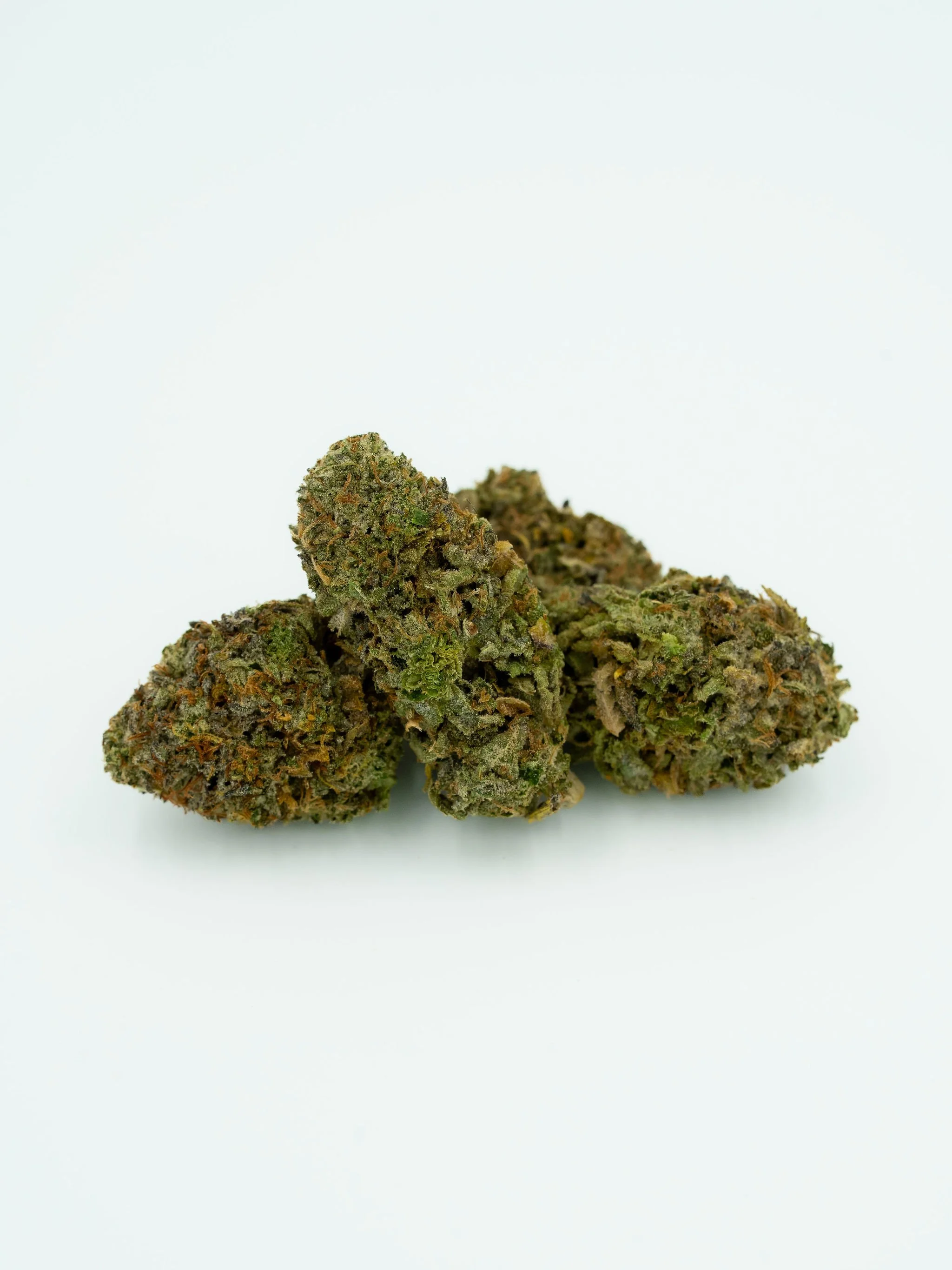 Close-up image of three cannabis buds on a white background.