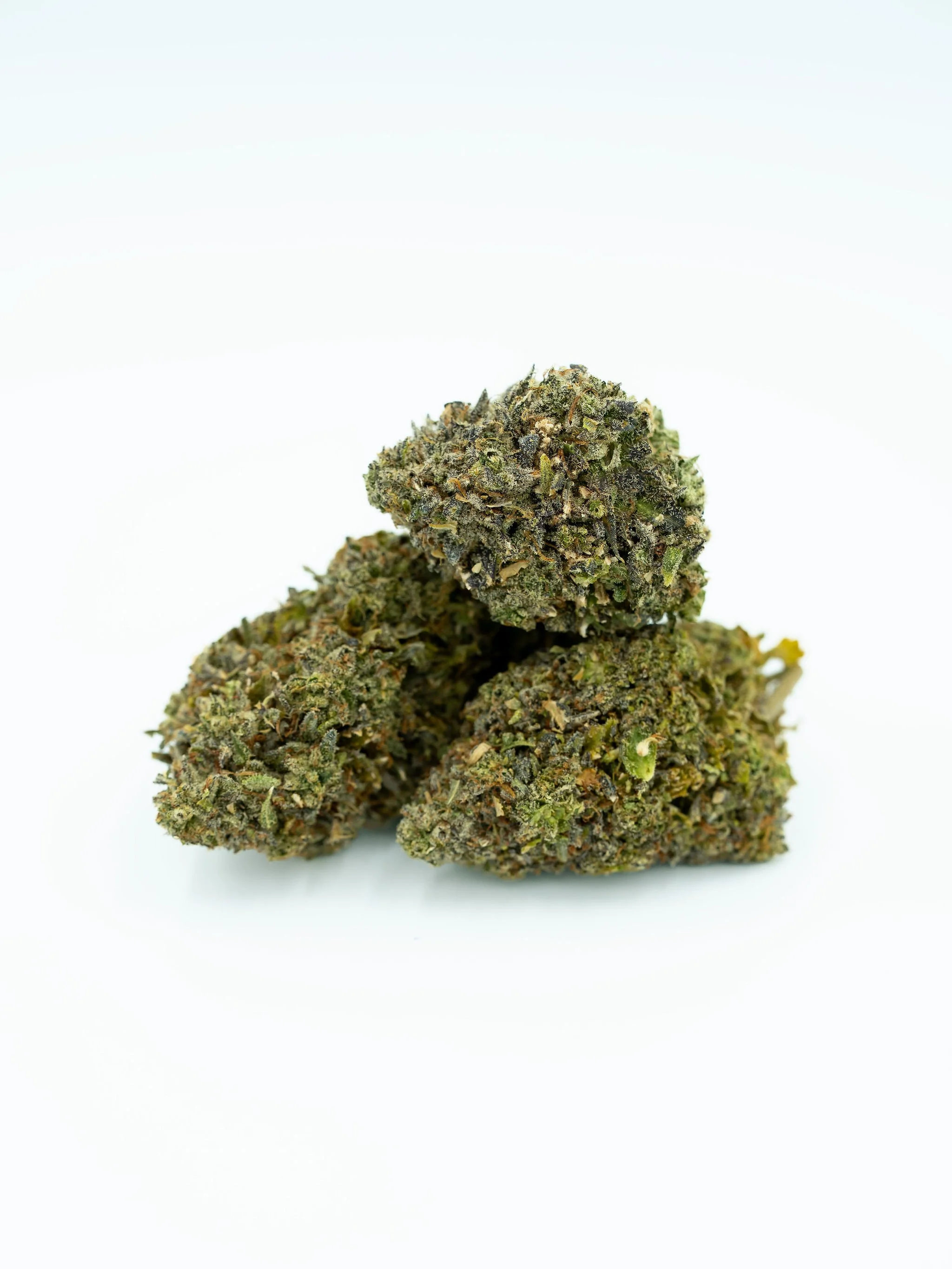 Three cannabis buds stacked on a white background.