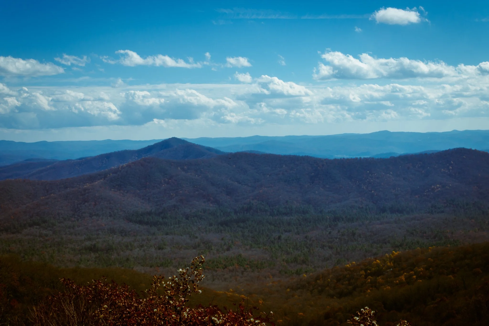 Scenic view of rolling blue and green mountains under a partly cloudy sky with scattered clouds.