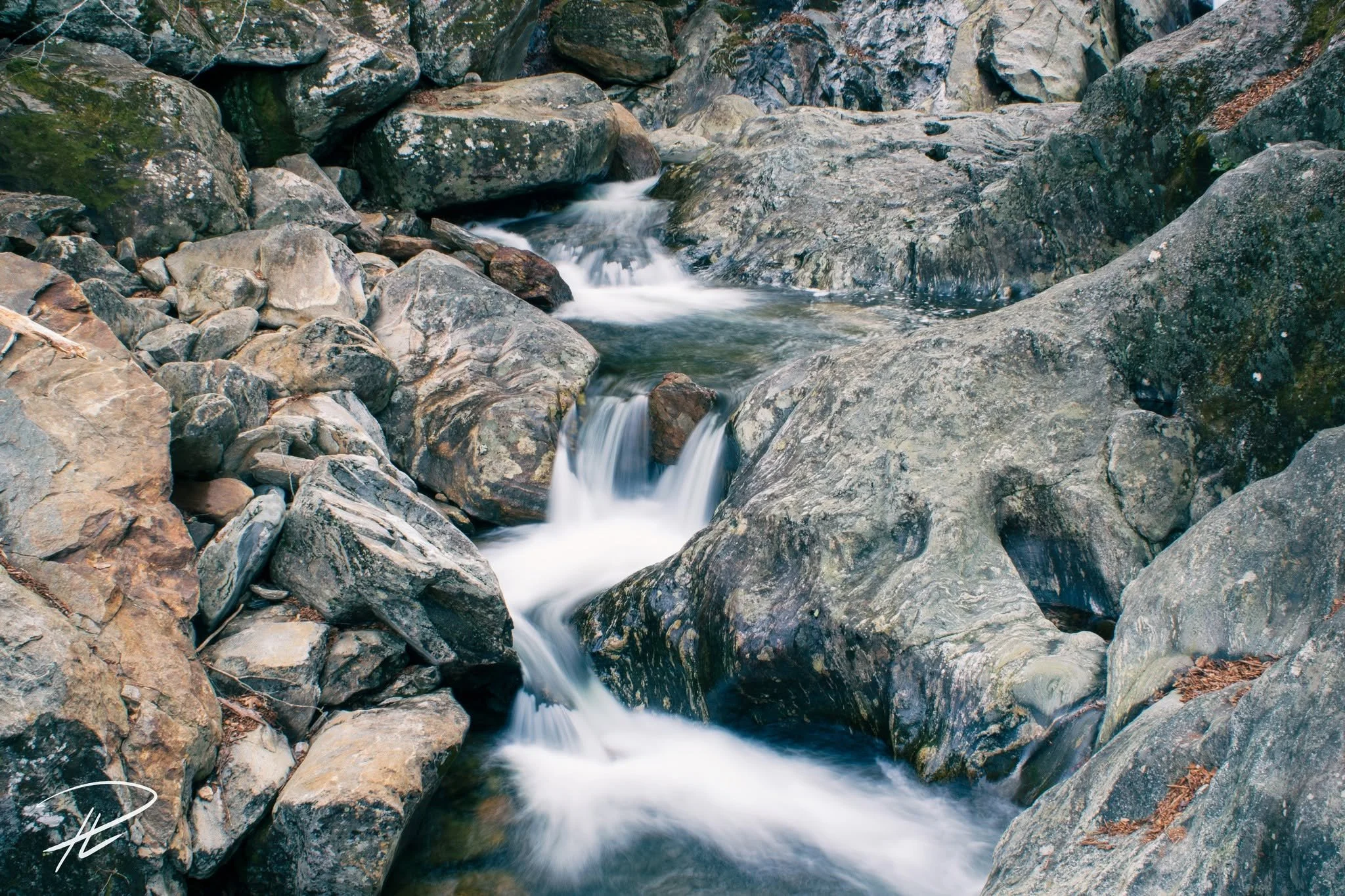 A small mountain stream flowing over rocks in a natural setting.