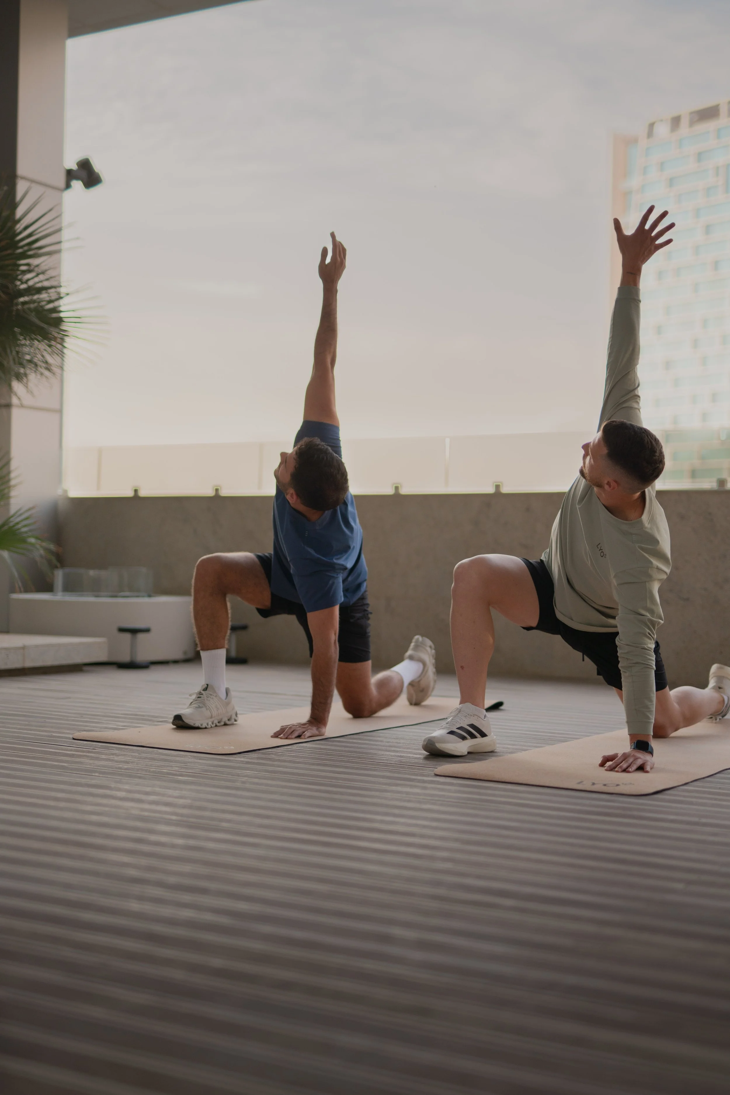 A close-up of wooden gymnastic rings hanging from black straps in a gym or fitness studio.