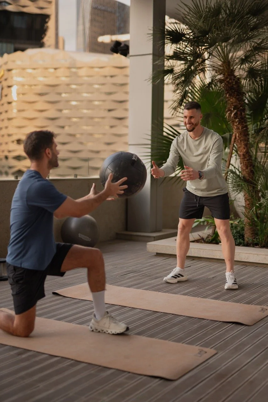 Trainer is throwing a medicine ball to his client
