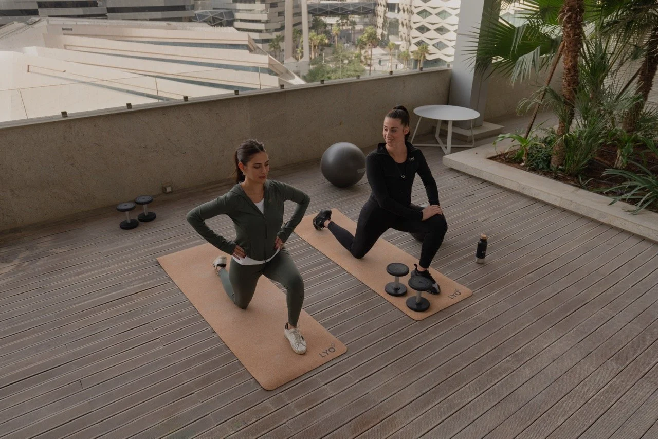 Two girls on yoga mats with weights next to them