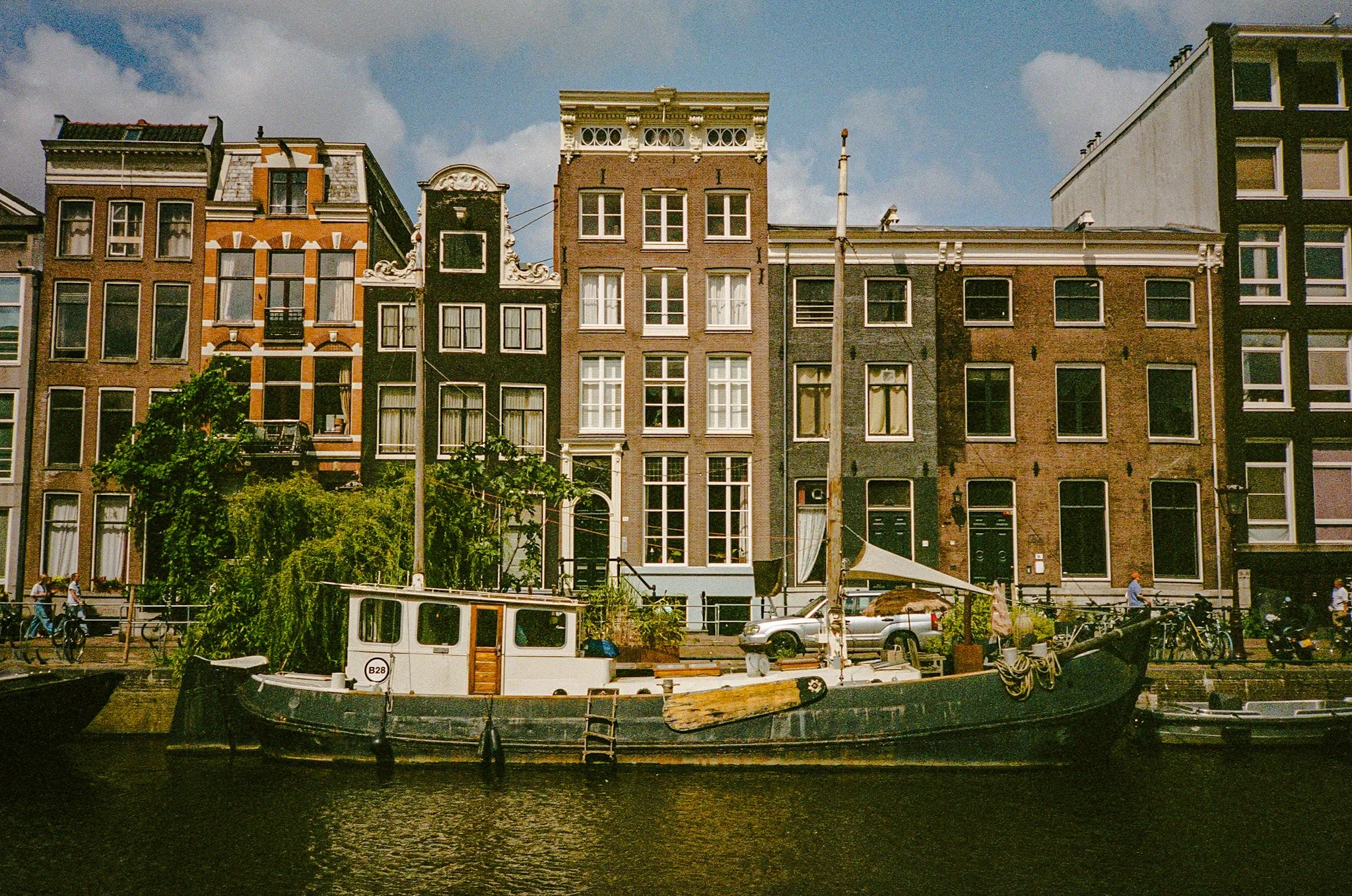 A canal with a boat docked along the edge, with tall, narrow buildings lining the waterfront in the background.