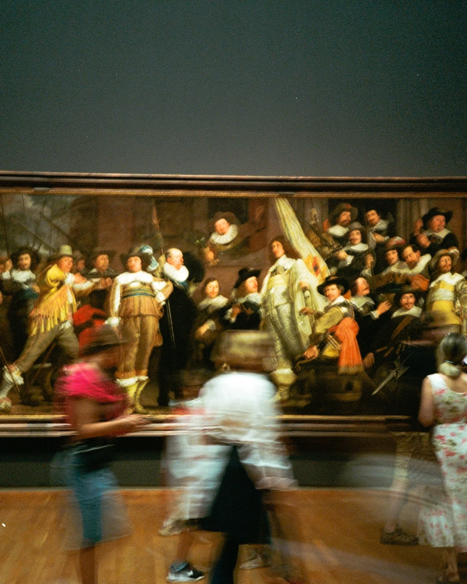 A painting depicting a historical scene with numerous figures in period clothing, engaging in a lively interaction, framed and hung on a gallery wall.