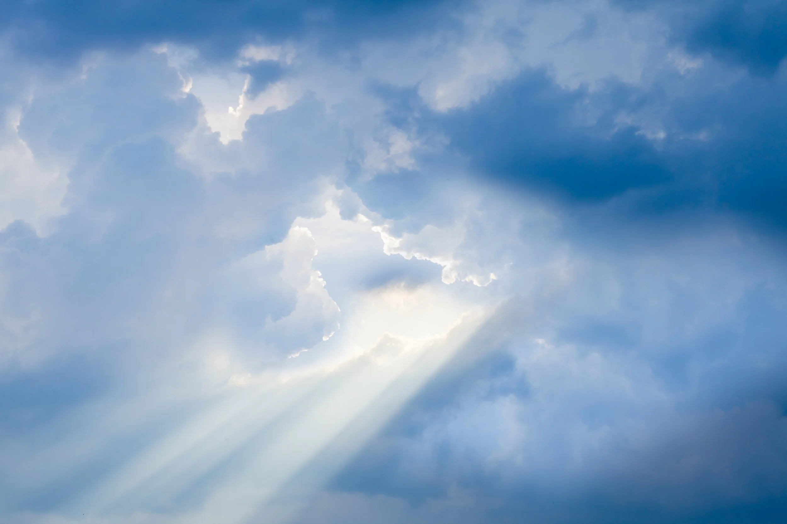 Sky with clouds and rays of sunlight shining through.