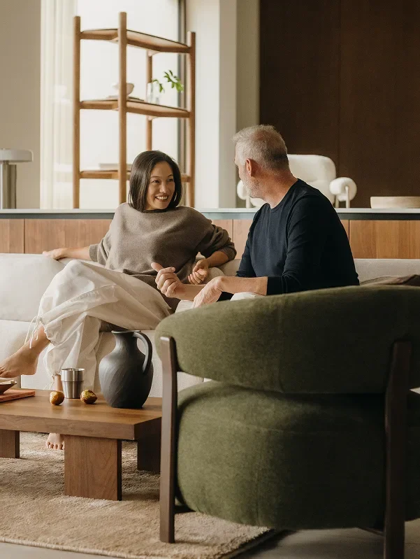 A man and woman sitting on a couch and laughing together in a living room.