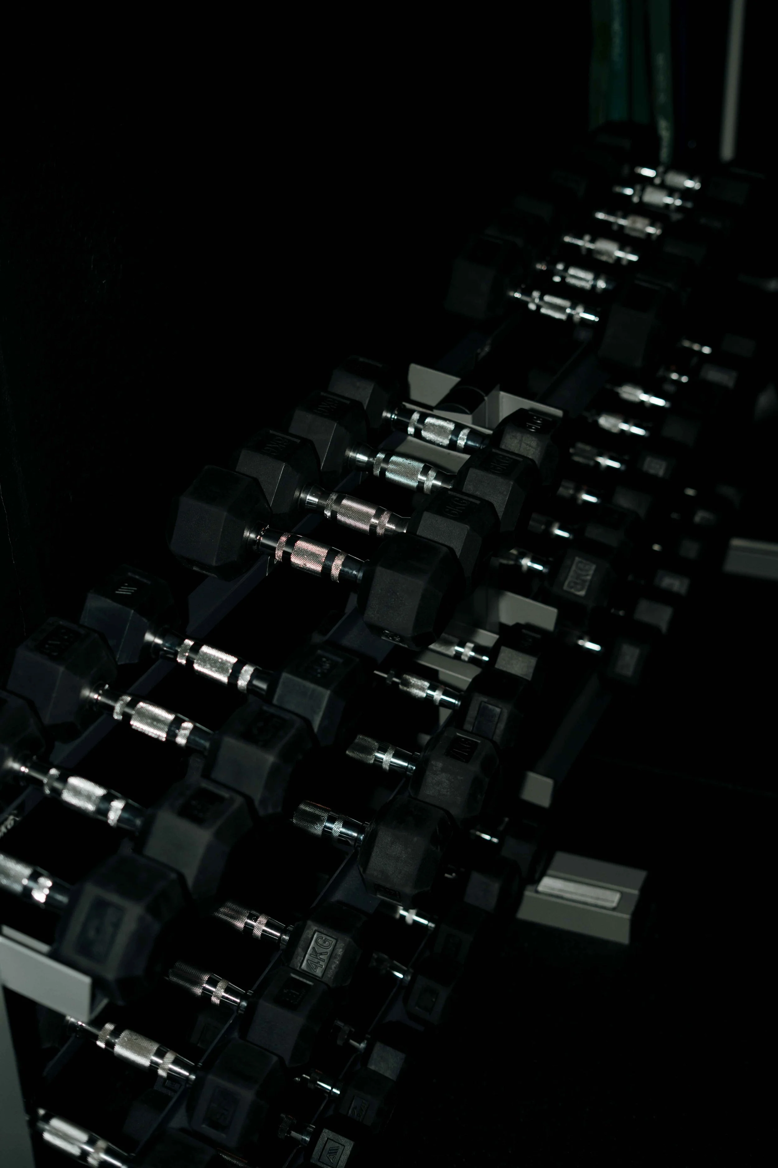 Fitnessstudio Bruchköbel: Mehrere schwarze Hanteln mit silbernen Griffen in einem Fitnessstudio.