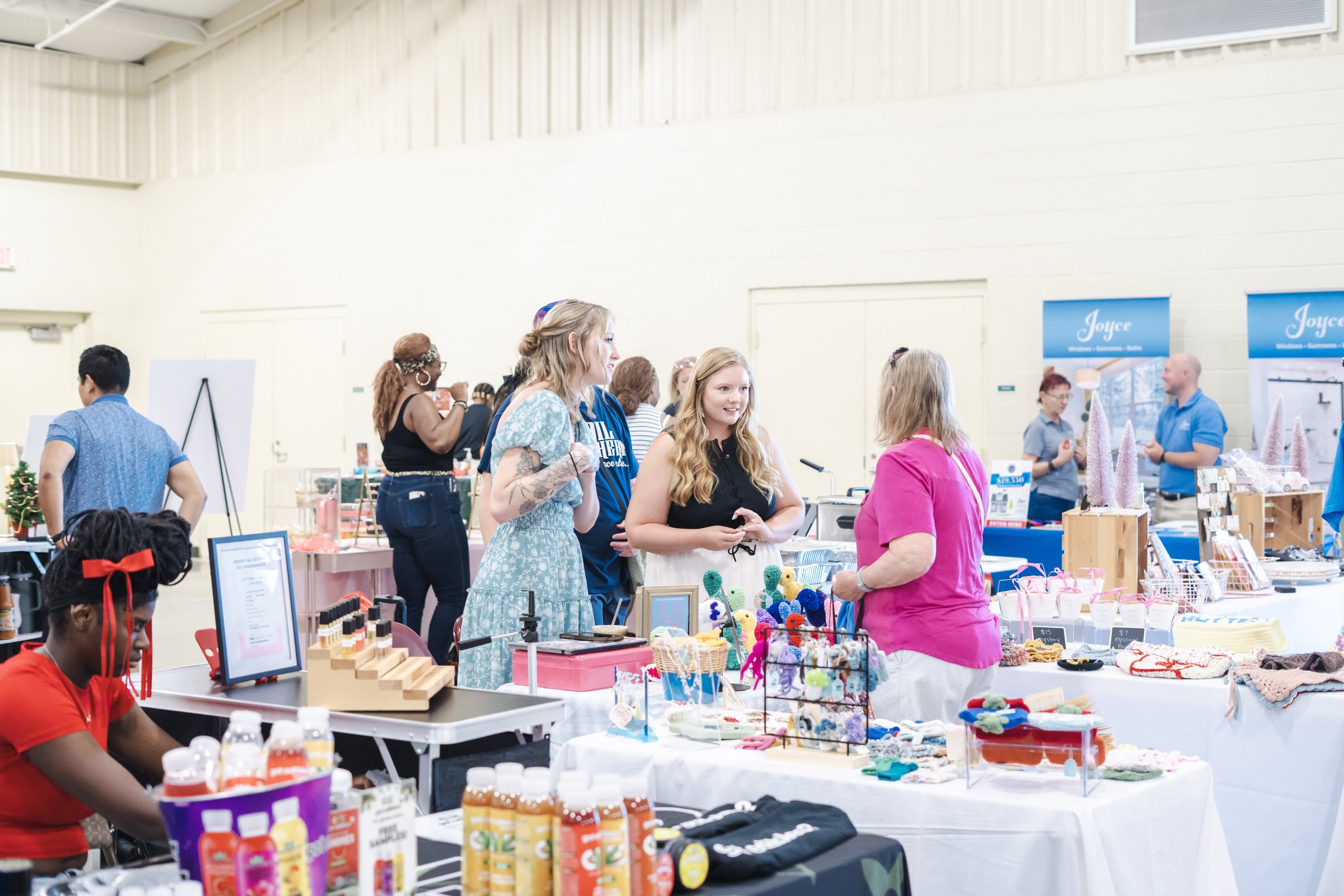 People shopping at a craft fair with various booths selling handmade items and crafts.