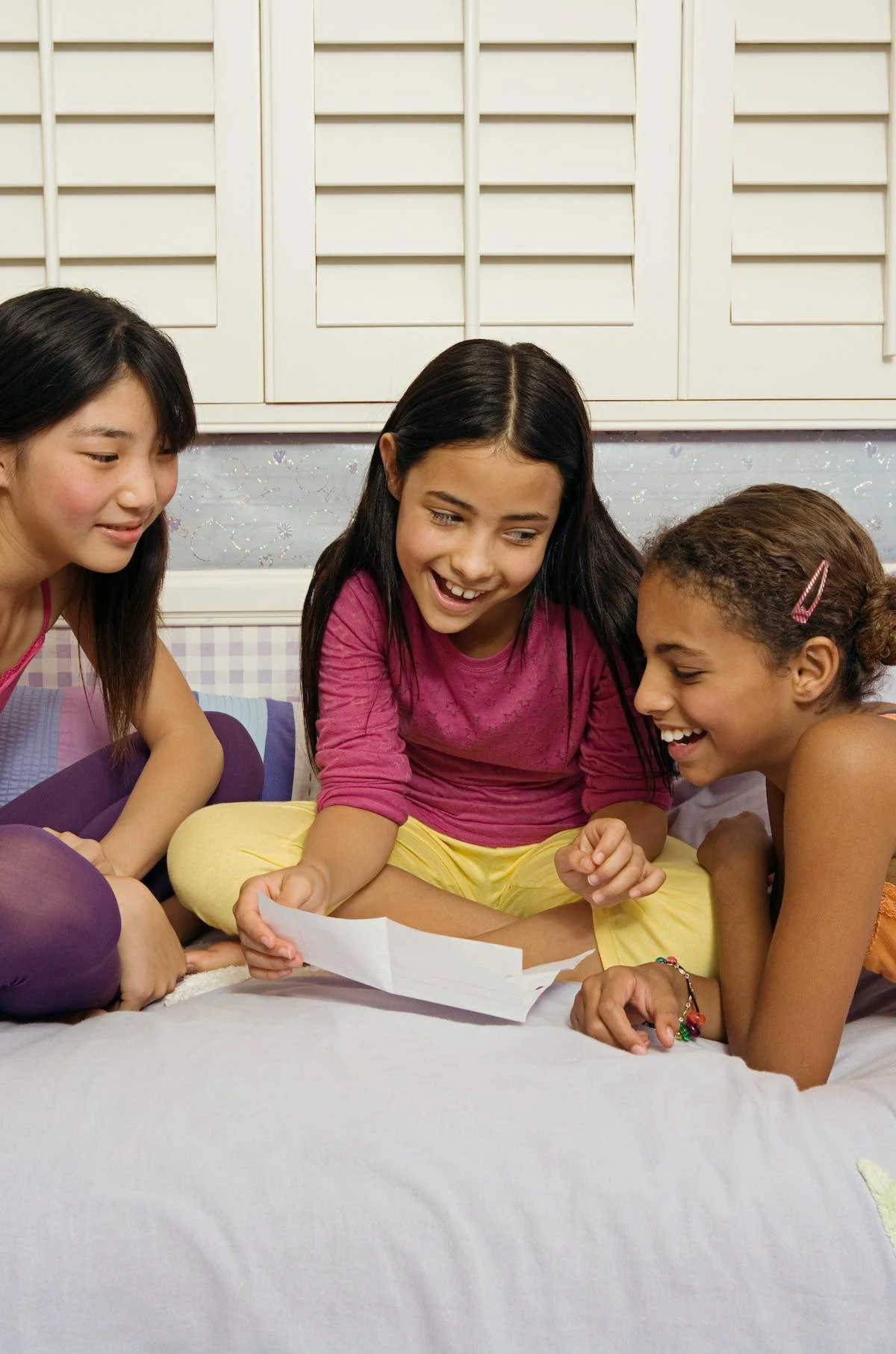 Three teenagers laughing and looking at a piece of paper.