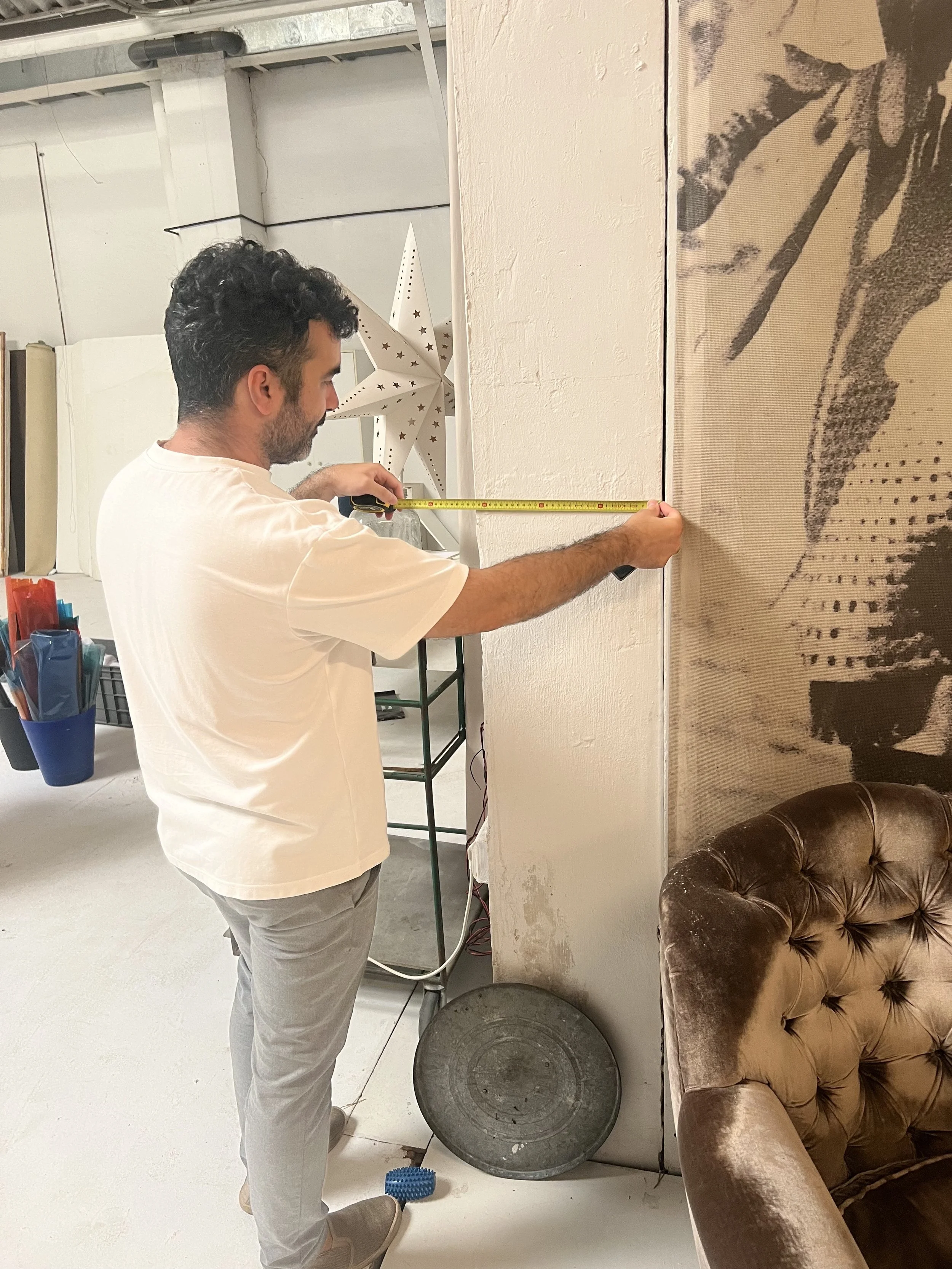 An architect is measuring a wall with a tape measure in the future Performance Hall space.
