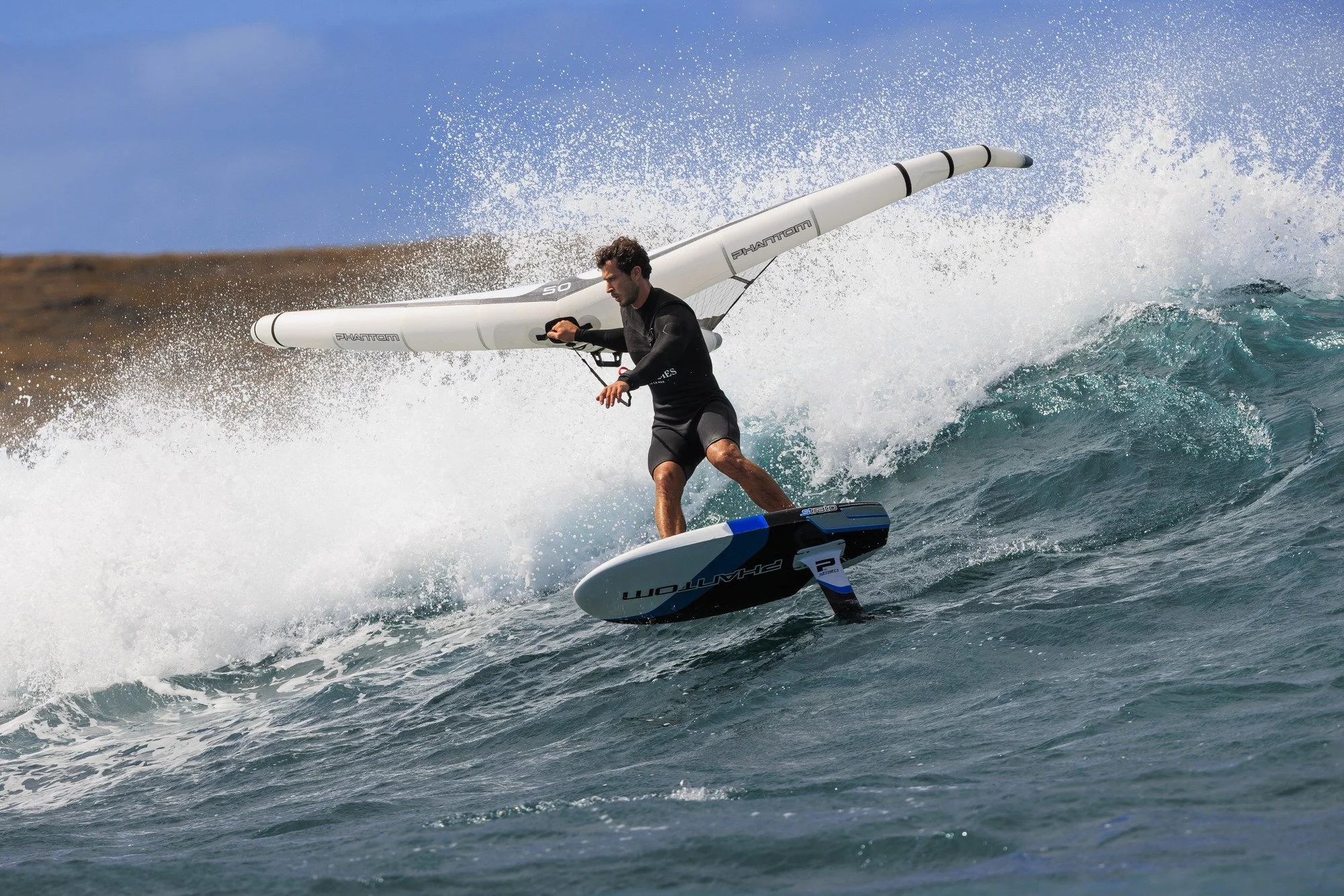Person wing surfing on a hydrofoil board in the ocean, holding a inflatable wing.