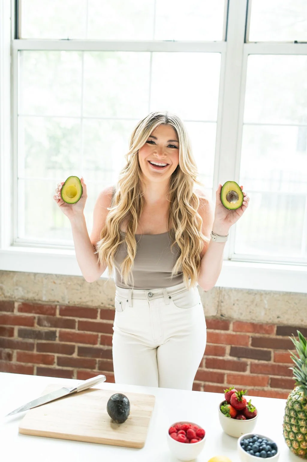 Haley smiling and holding halves of avocado