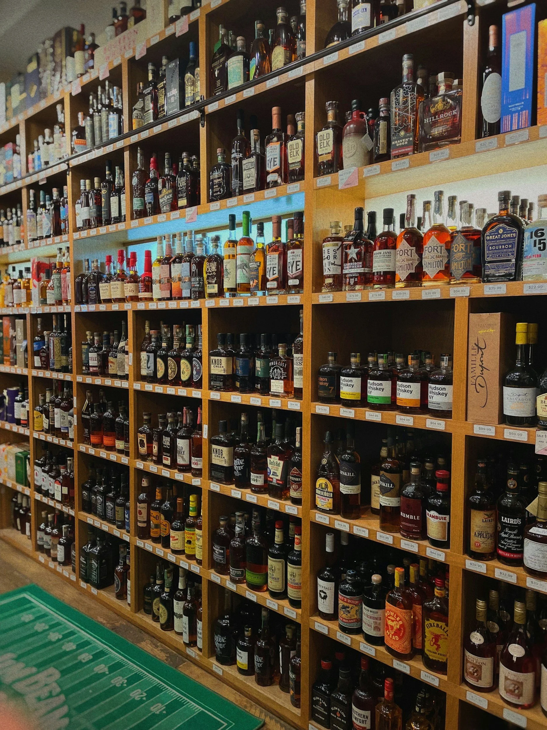A liquor store shelf filled with various bottles of whiskey and other spirits, organized by type and brand.
