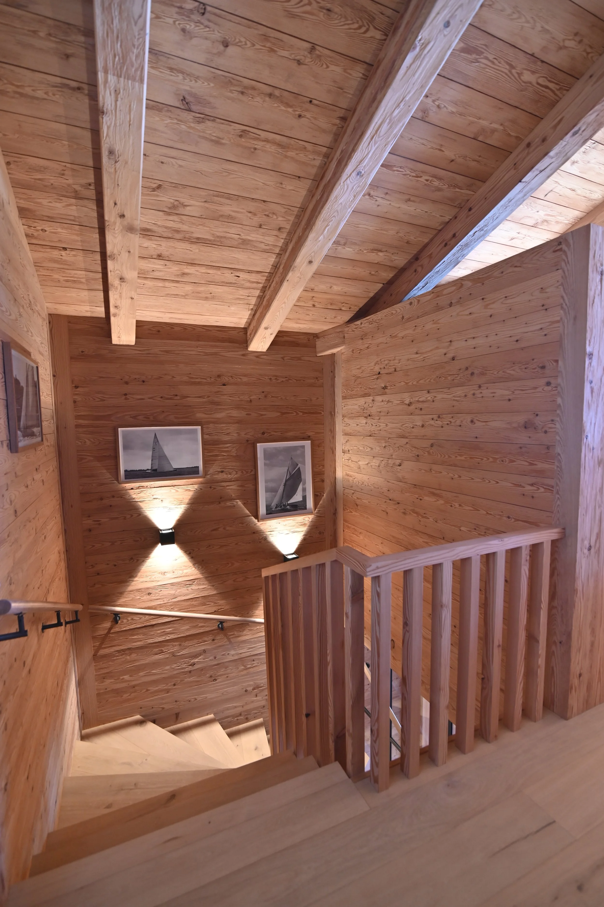 Innenansicht eines Treppenhauses aus Holz mit Wandbildern von Segelbooten.