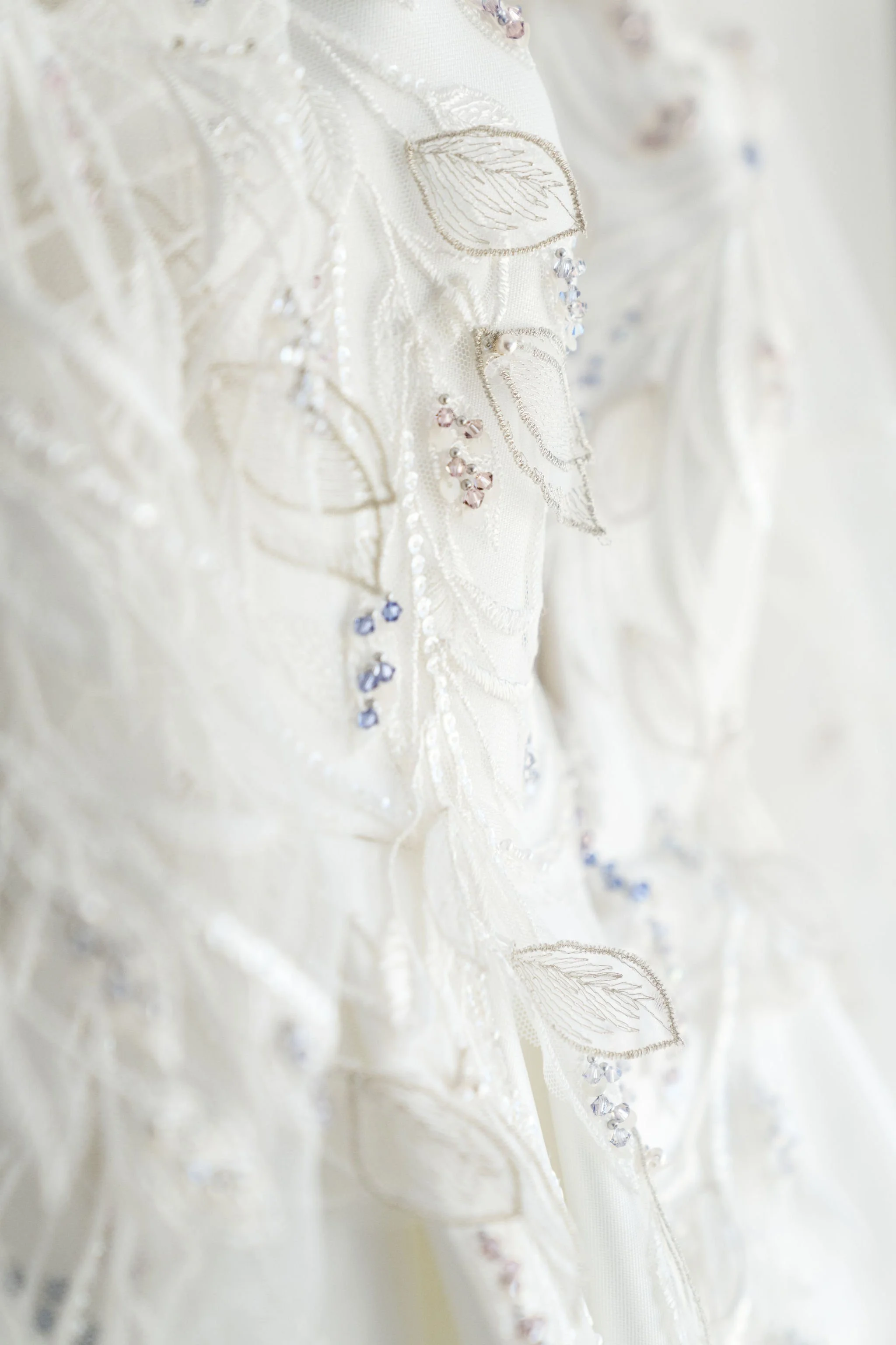 Close-up of an ornate wedding dress with intricate embroidery, beading, and floral patterns.