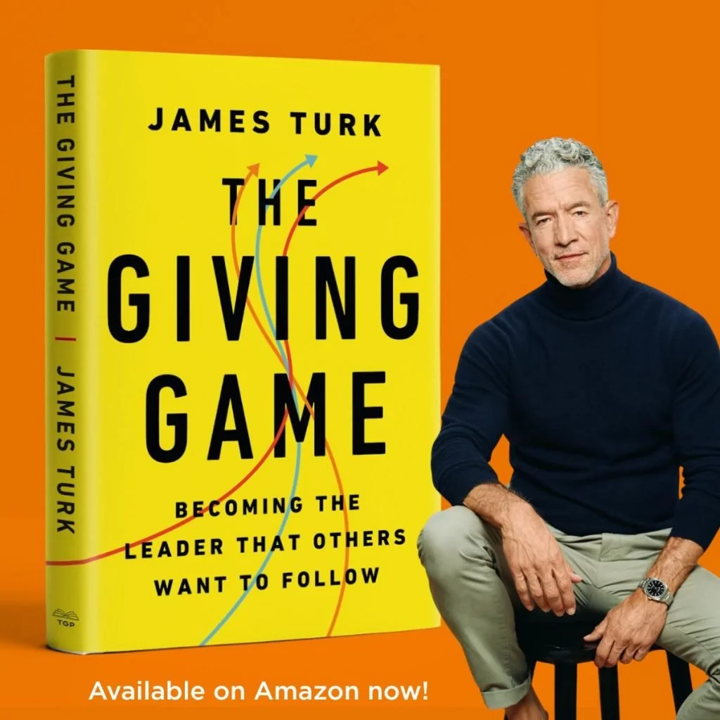 Cover of the book titled 'The Giving Game' by James Turk. The cover is yellow with black text and colorful arrows. There is a man with gray curly hair, wearing a black turtleneck and beige pants, sitting to the right of the book against an orange background. The text at the bottom indicates the book is available on Amazon.