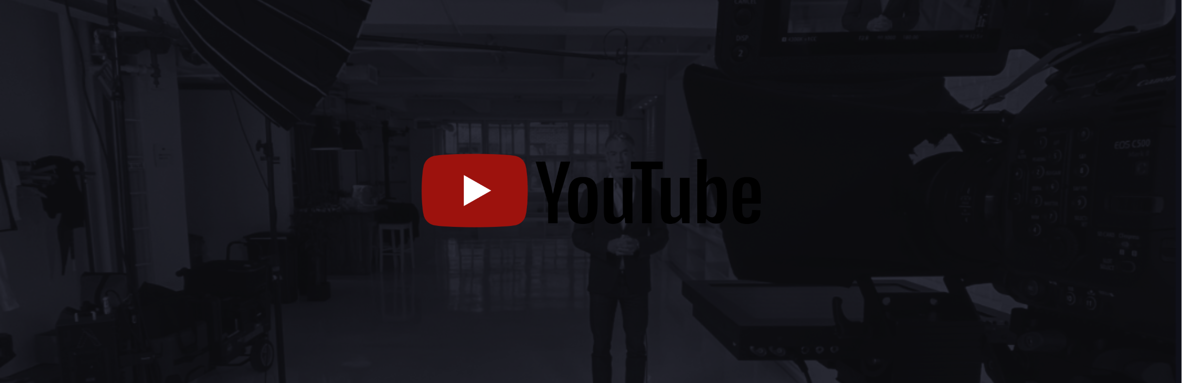 A person standing in a studio with lighting equipment, cameras, and a large YouTube logo overlayed on the image.