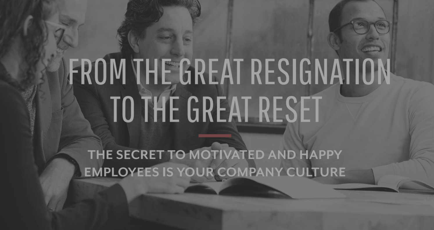 A group of four diverse coworkers smiling and working together at a table in an office setting.