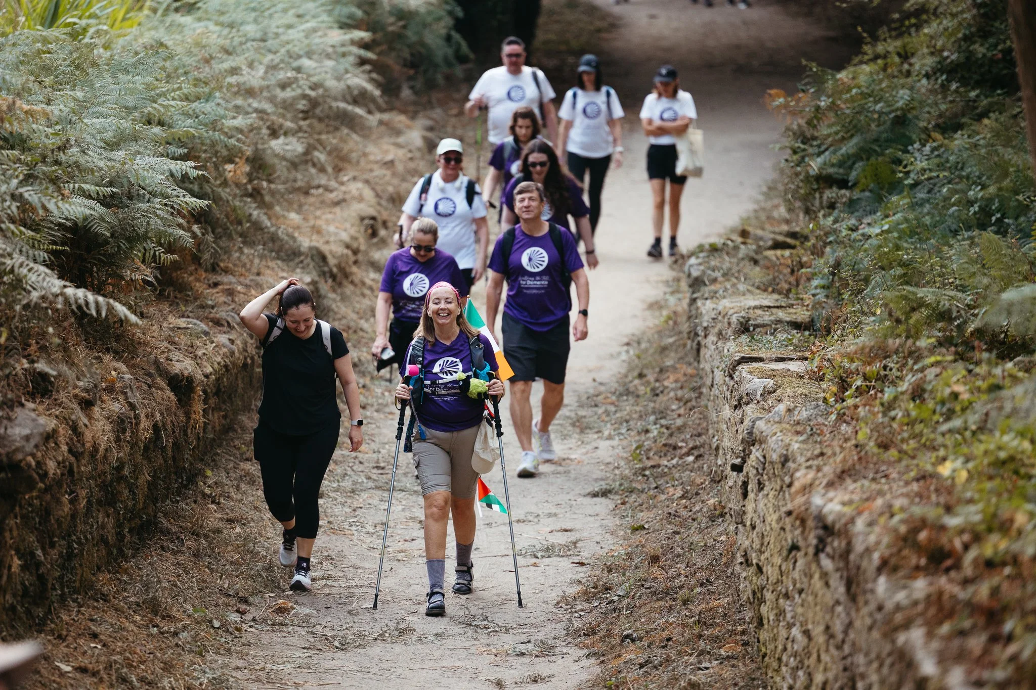 Group of people hiking on a dirt trail surrounded by foliage.