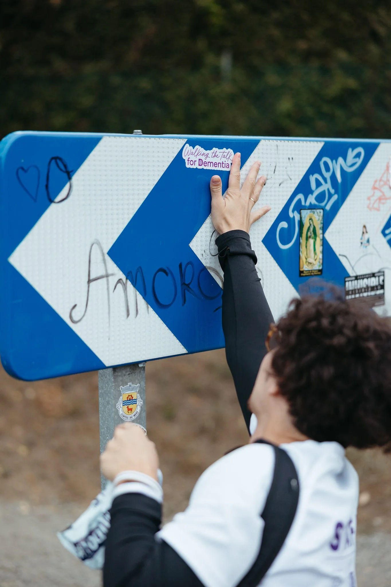 Person attaching a sticker on a road sign with the word "Amor" visible