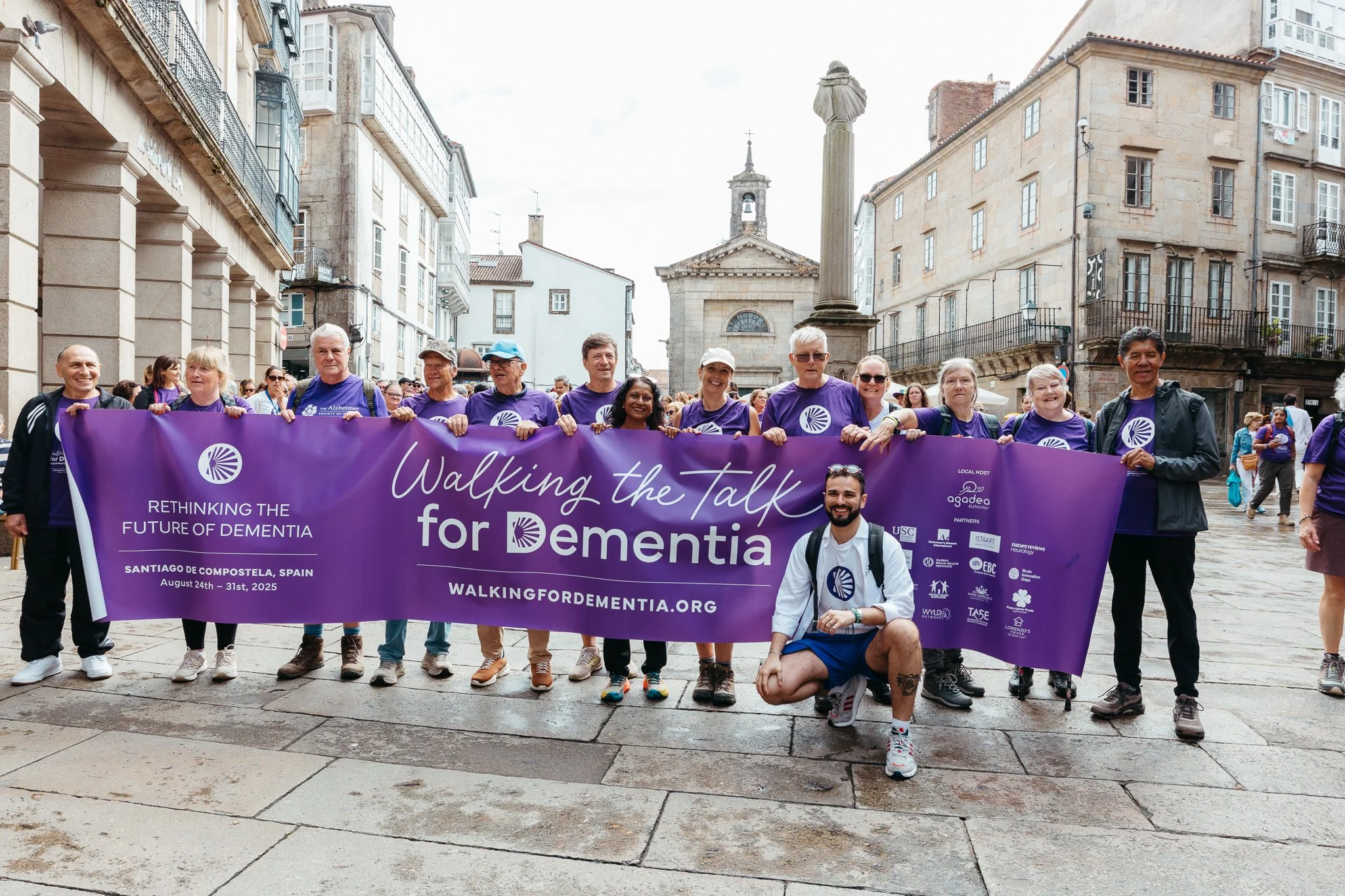 Group of people holding a purple banner that reads 'Walking the Talk for Dementia' during a community event in Santiago de Compostela, Spain, August 24-31, 2025.