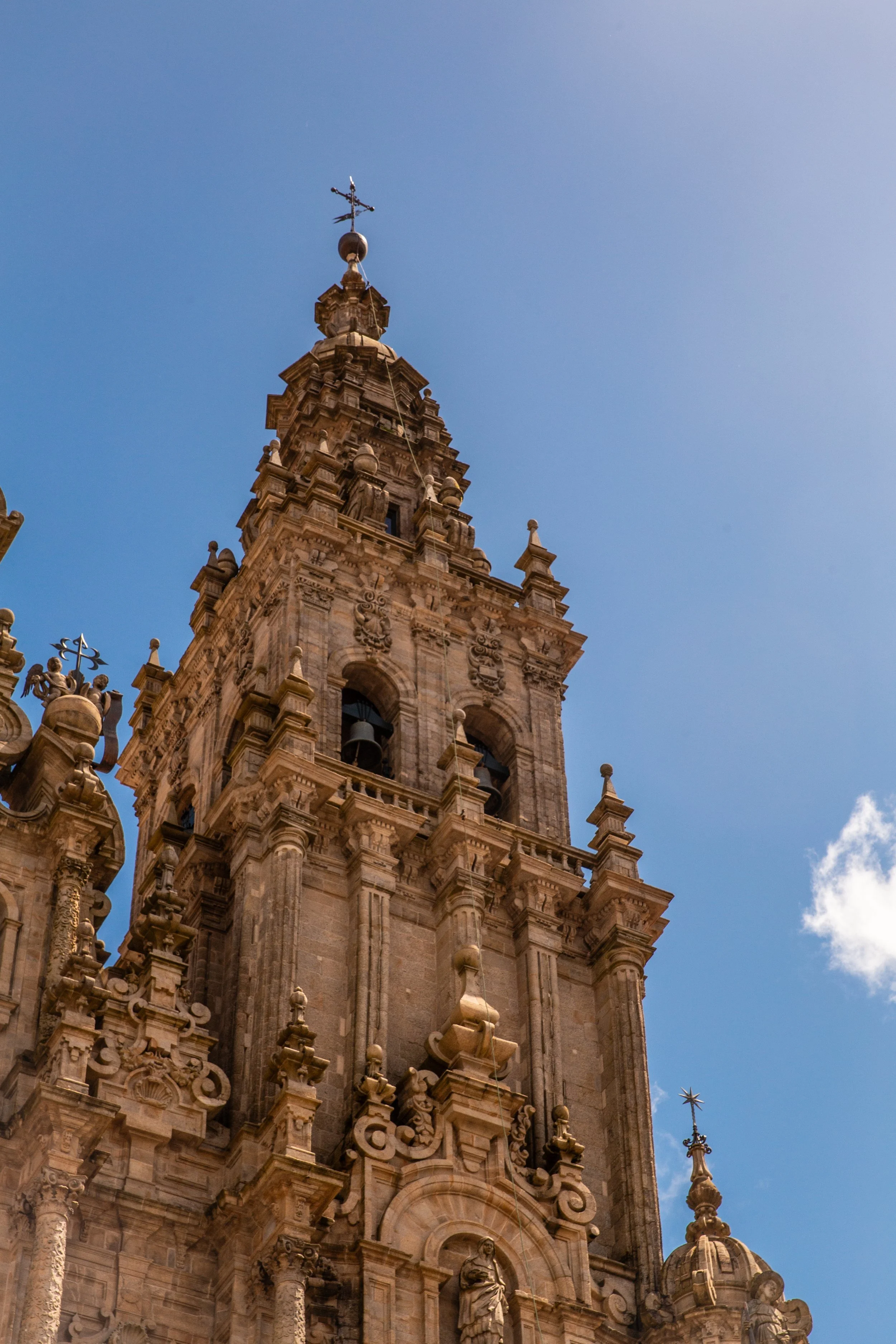 Detailed view of a historic church or cathedral bell tower with ornate architecture against a bright blue sky.
