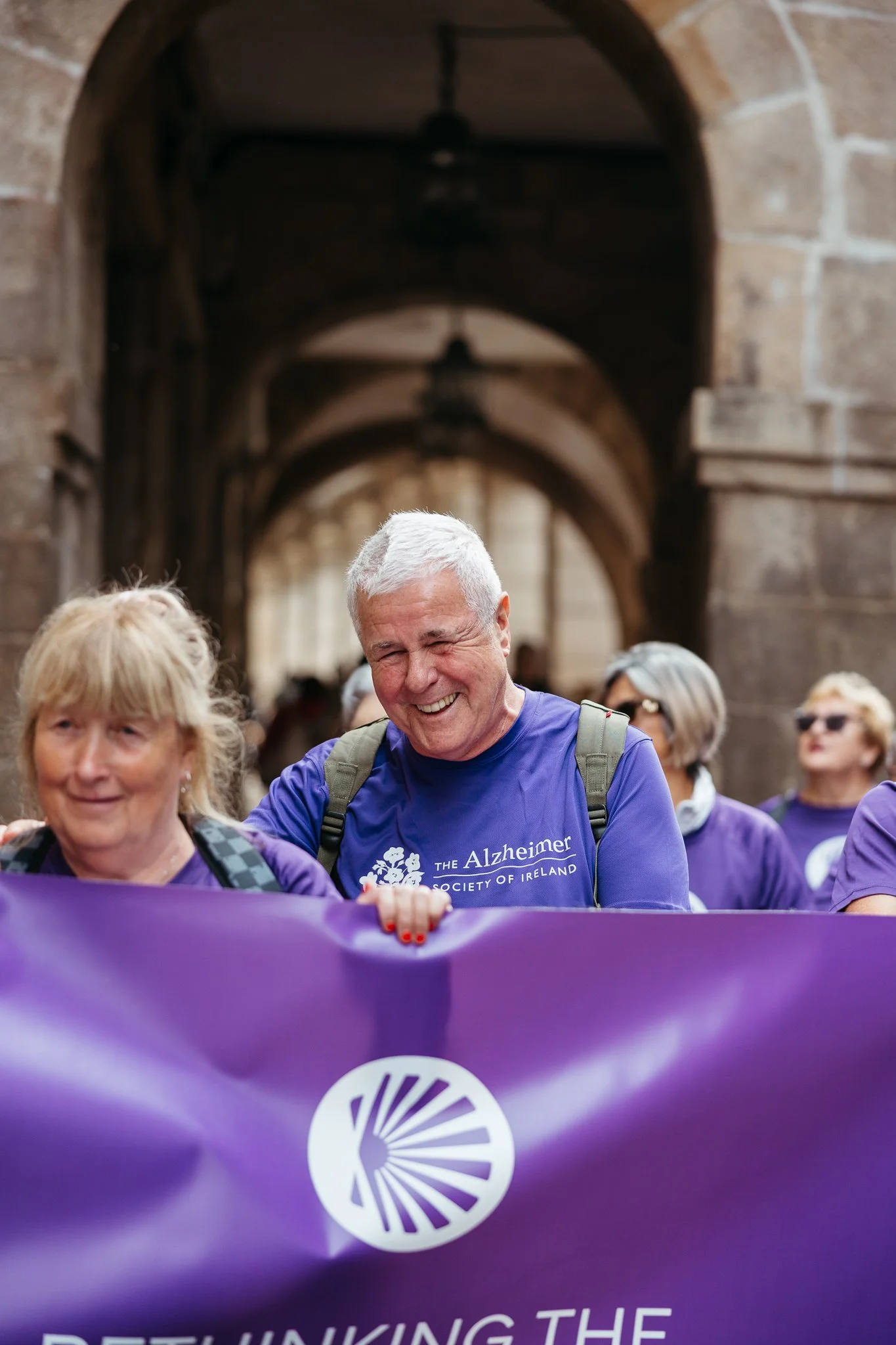 Group of senior adults participating in a walkathon holding a purple banner with a logo and text supporting Alzheimer's awareness.