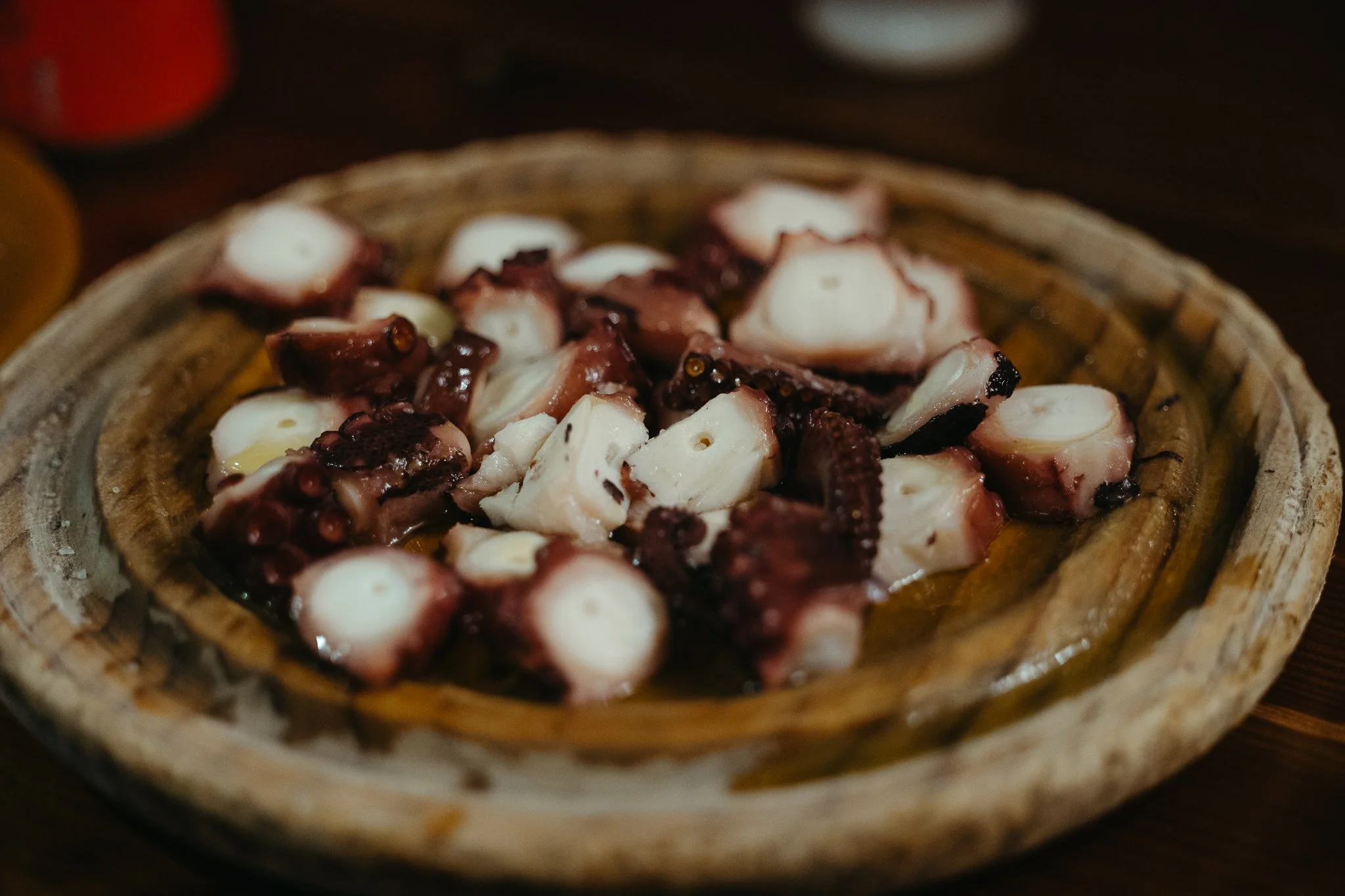 Chopped octopus tentacles on a rustic wooden plate.