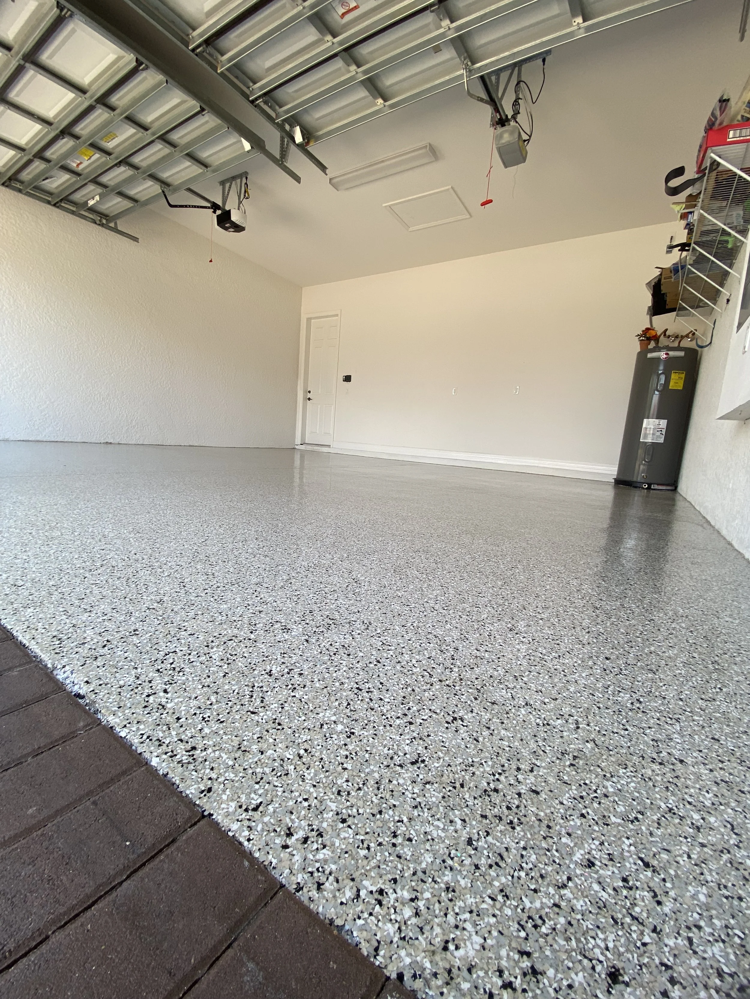 Empty garage with epoxy-coated floor, white walls, and an open garage door.