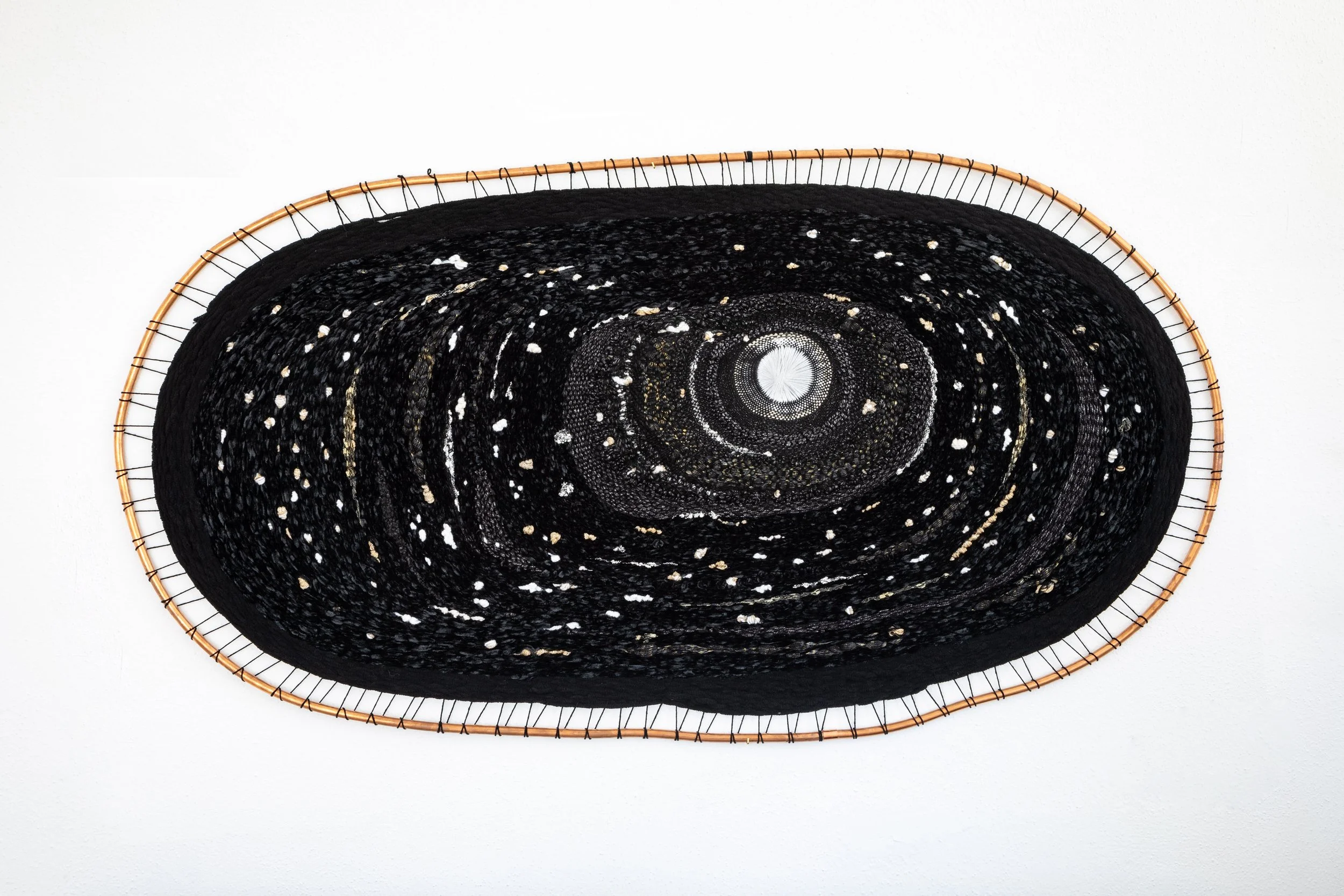 Oval woven basket with a black and white woven pattern inside, on a white background.