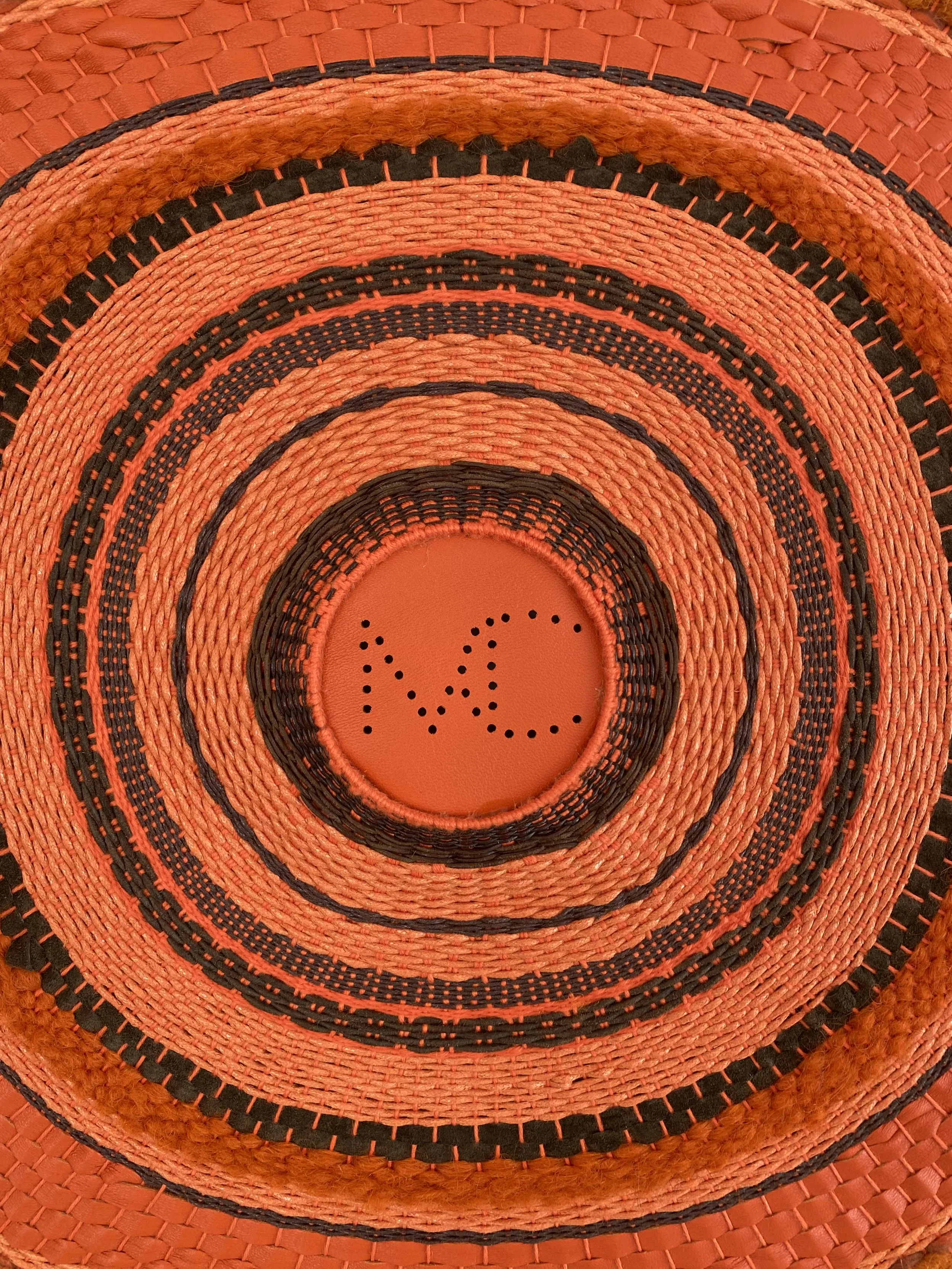 Close-up of a woven sunhat with the word 'VIC' spelled out using small holes in the center of the hat.