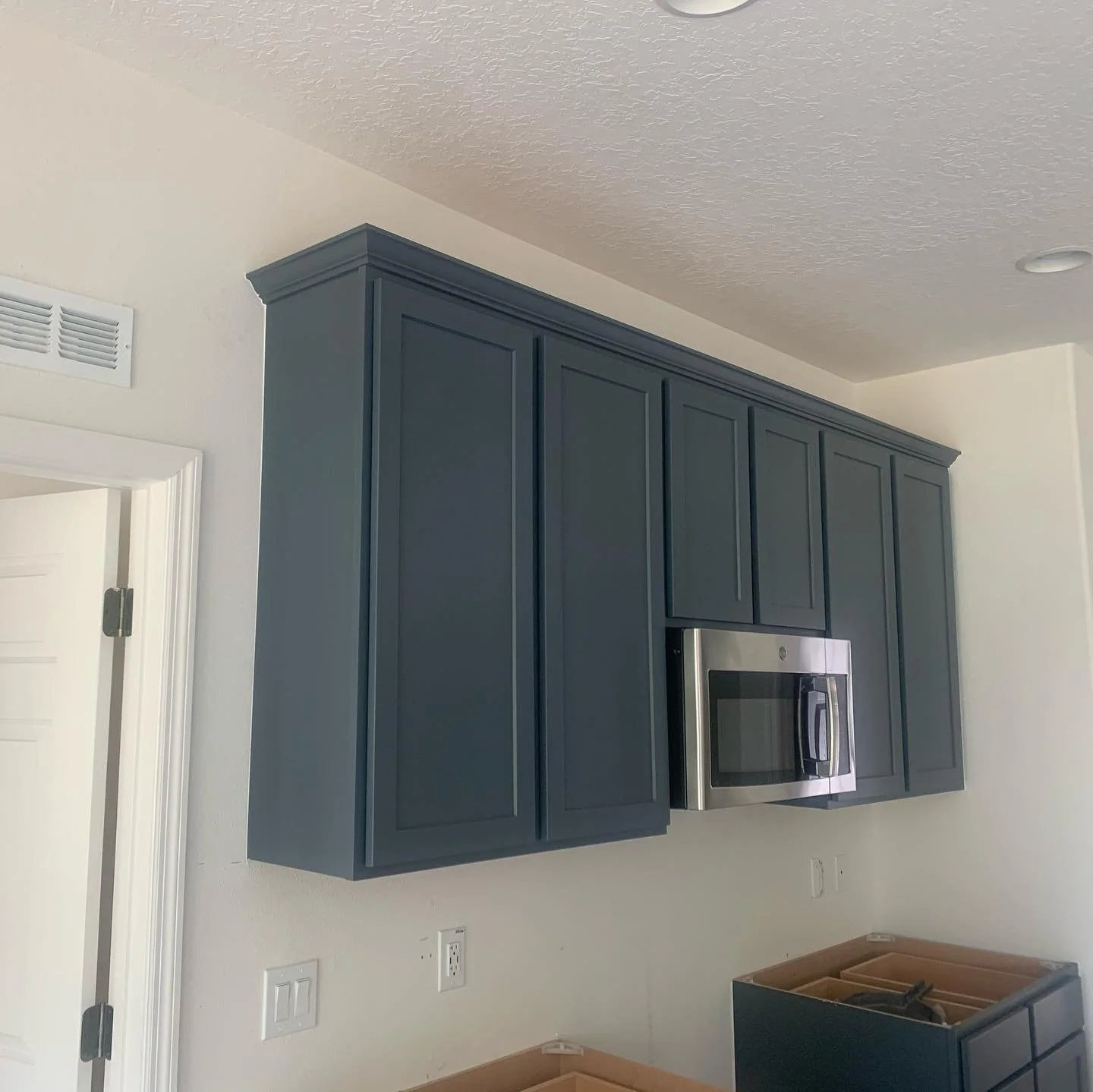 Kitchen cabinets and microwave installed with a partially assembled cabinet below.