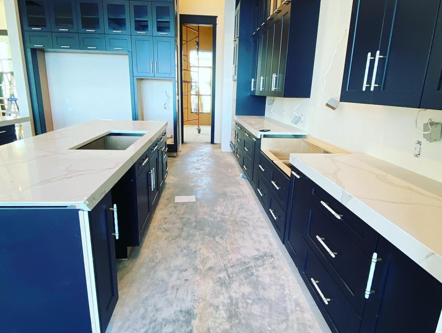 Kitchen with dark blue cabinets and light-colored countertops, under construction.