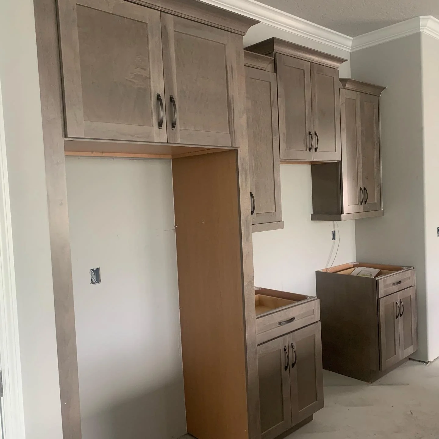 Incomplete kitchen cabinets in a new home under construction, with some doors installed and others missing.
