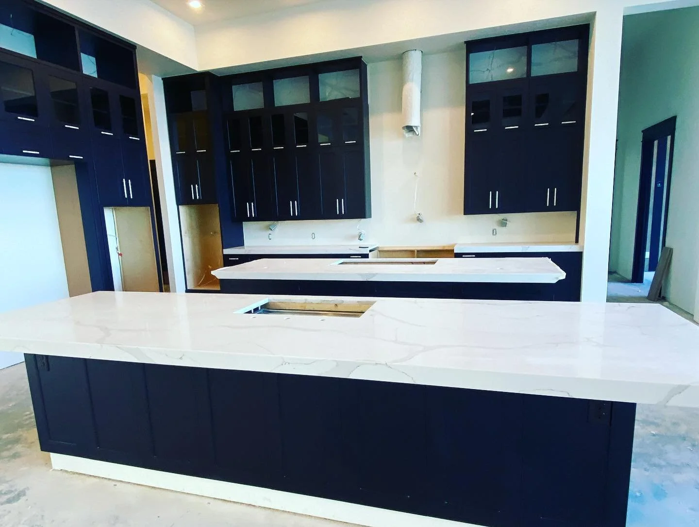 Kitchen with black cabinets, white countertops, and an island under construction.