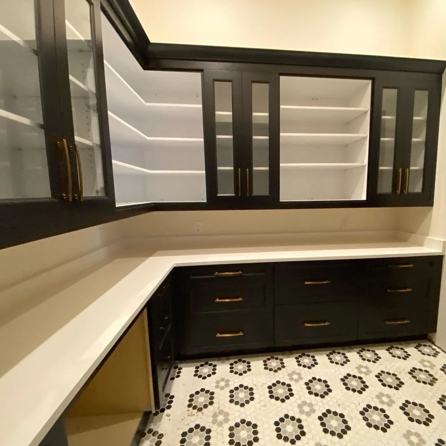 Kitchen with black cabinets, white countertops, and patterned black and white tile flooring.