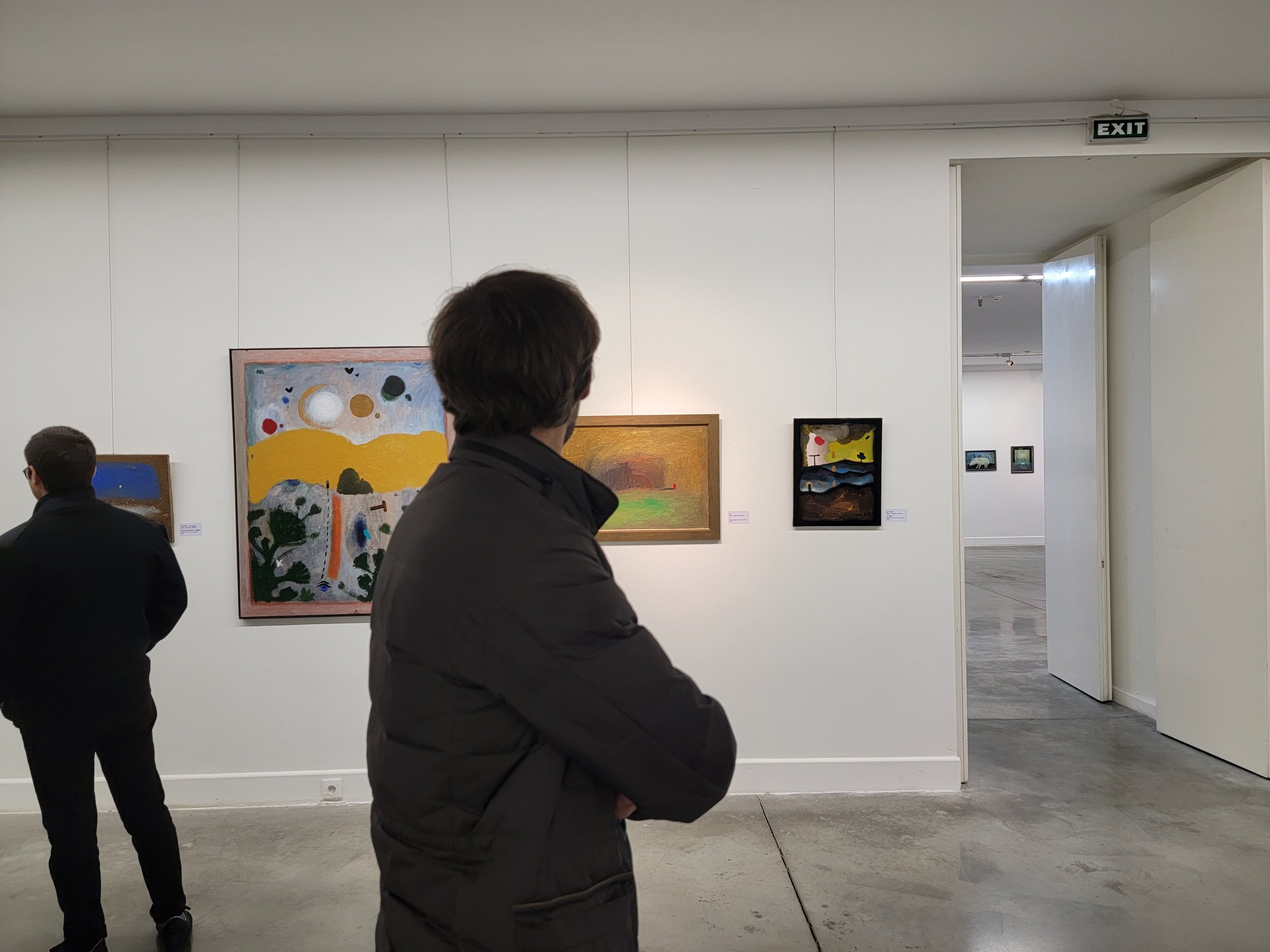 Visitors viewing abstract art paintings in a gallery with white walls and a concrete floor. Anton Balanchivadze 
