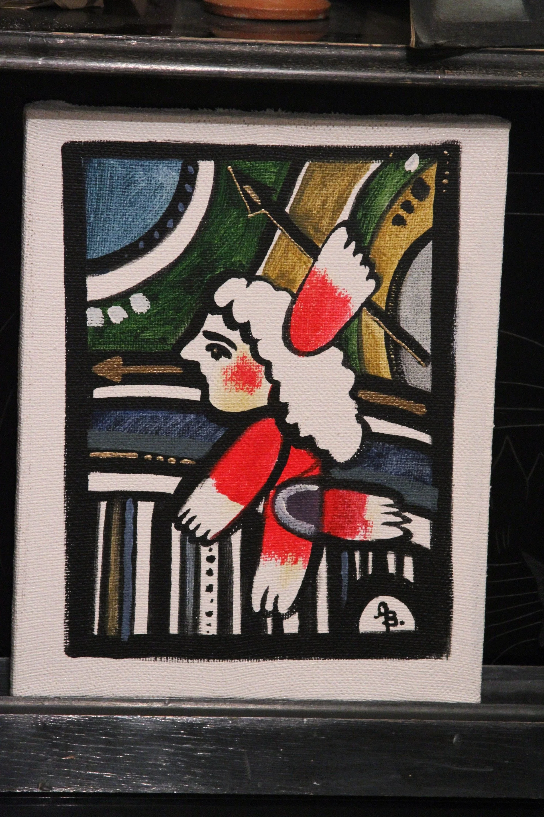 A colorful abstract painting of a woman with curly hair and red cheeks, holding a paintbrush, depicted with bold black outlines and vibrant colors.