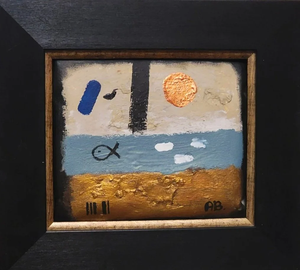 Abstract painting with a textured gold and brown ground, a blue water section with white clouds, a black fish, a black bird, a large orange sun, a small white moon, a black vertical stripe, and a blue roller brush stroke, all framed in a wooden frame