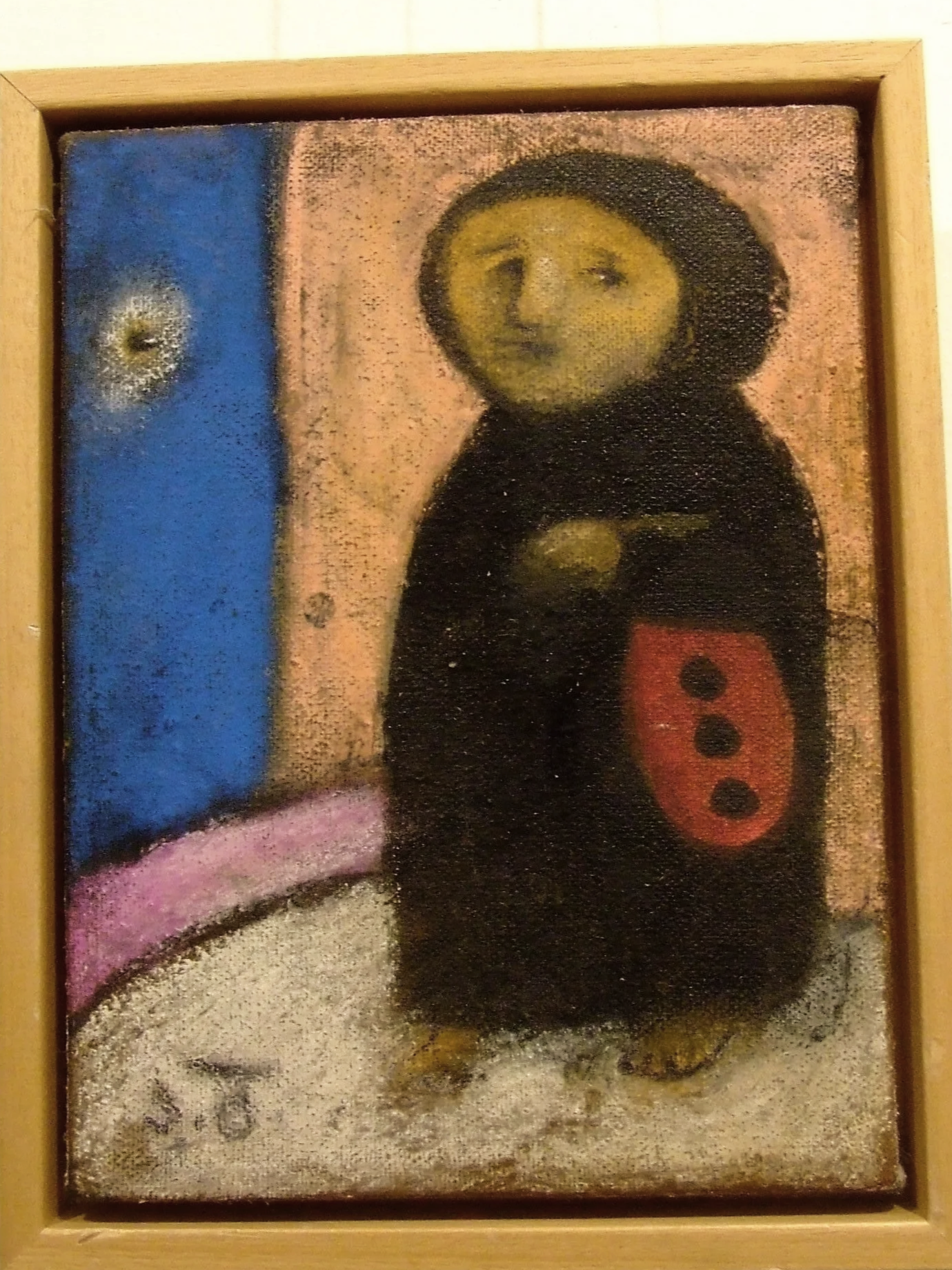 A painting of a figure with a yellow face and black body, holding a red shield with three black dots, standing on a white ground against a background of pink and blue with a small white and yellow object in the blue area.