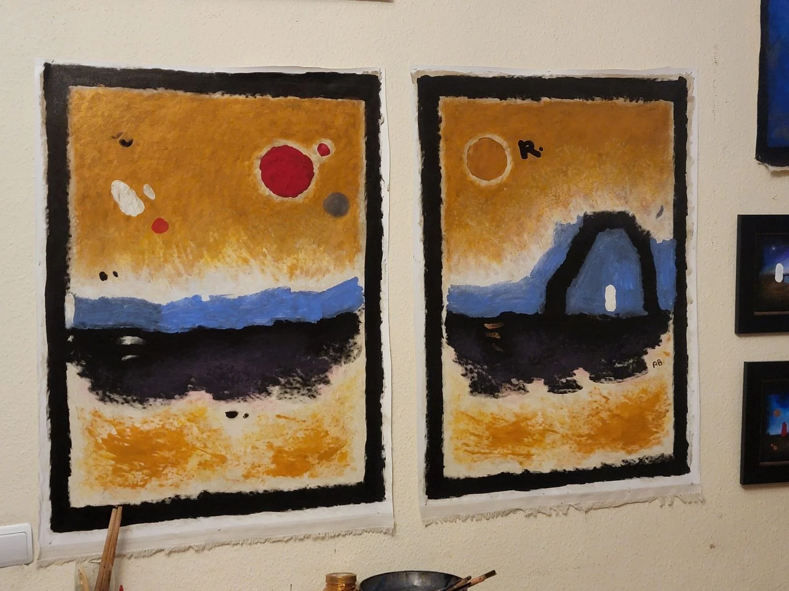 Two abstract paintings side by side depicting a landscape with a mountain and sky, with various colored circles representing celestial bodies.