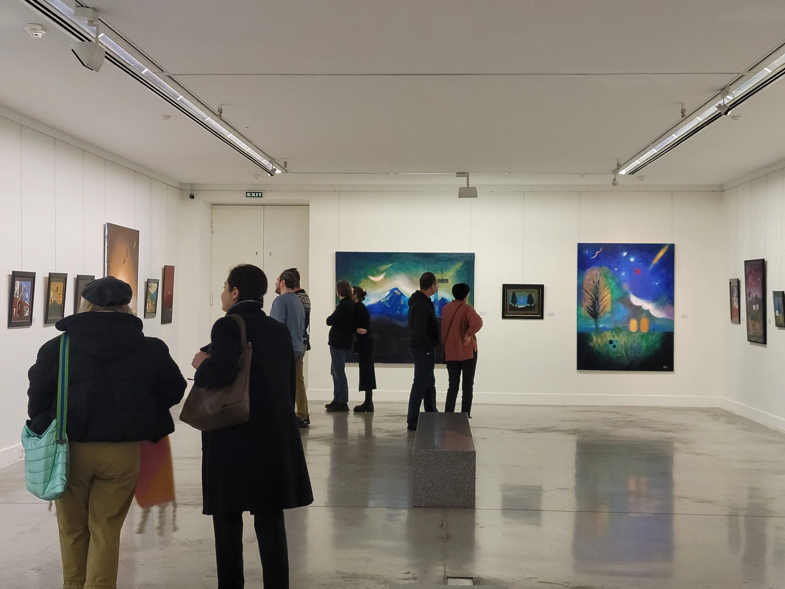 People viewing Anton Balanchivadze's artwork in nationall gallery of georgia, with white walls and a concrete floor. Exhibition "Seen at the bridge" , in Tbilisi , Georgia