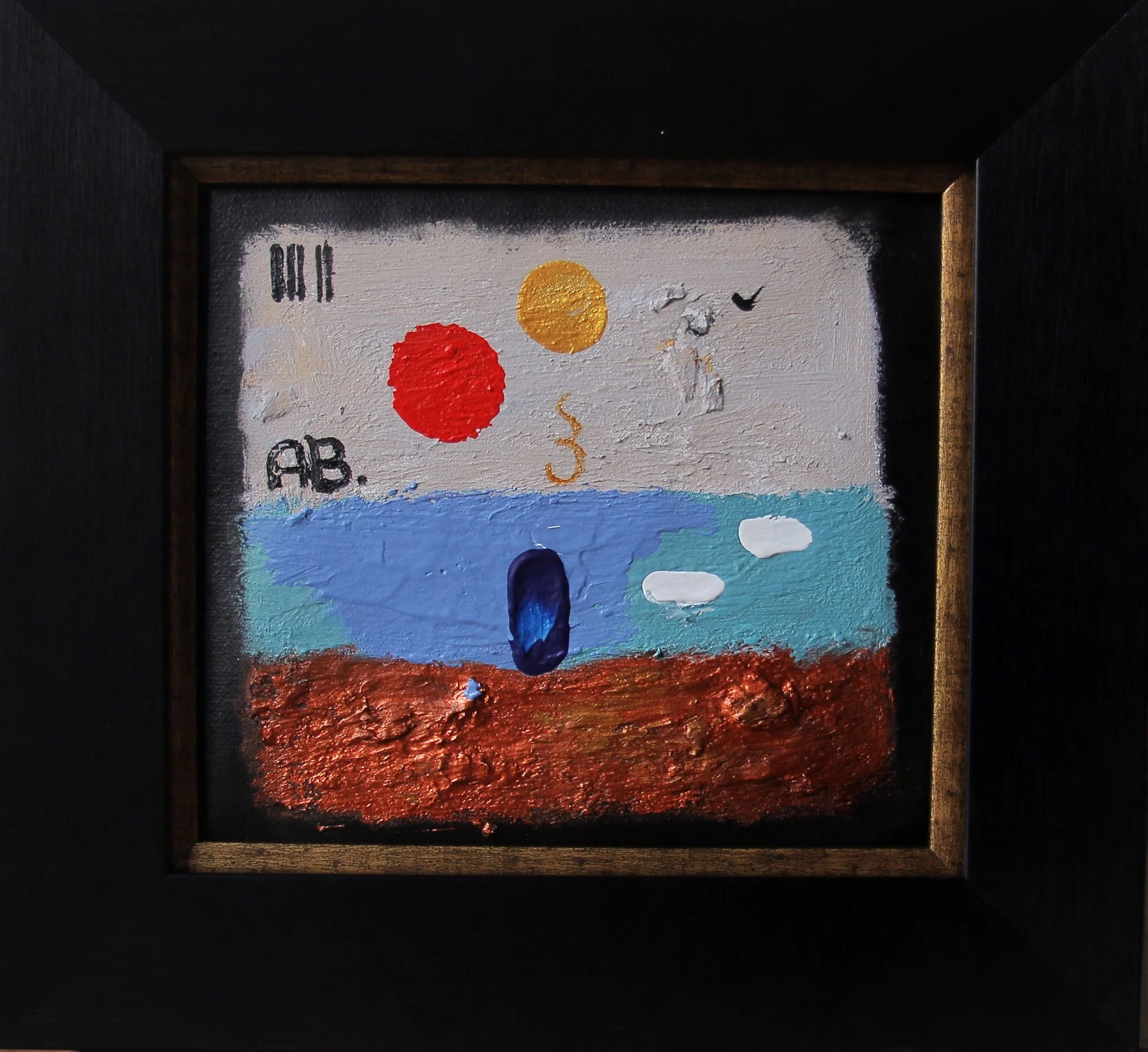 Mixed media artwork depicting a landscape with a rocky foreground, a blue water body, and a white sky featuring two colored circles, a spiral, and three small clouds, all enclosed in a black wooden frame.
