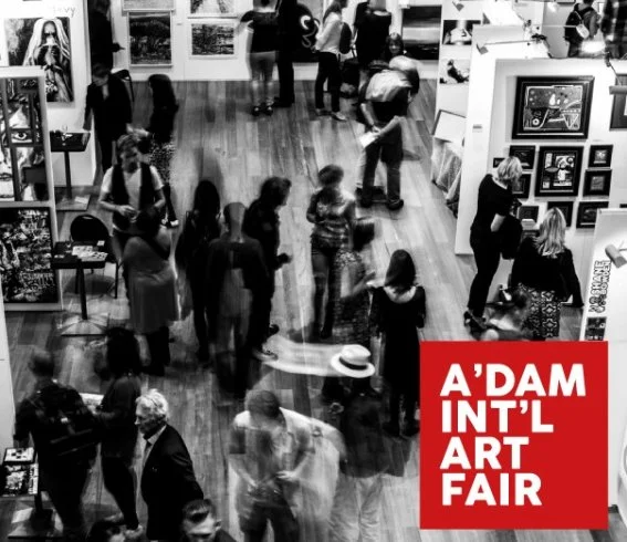 People browsing art at the A'Dam International Art Fair in an indoor venue with artworks displayed on panels and walls. Artist Anton Balanchivadze in the center 