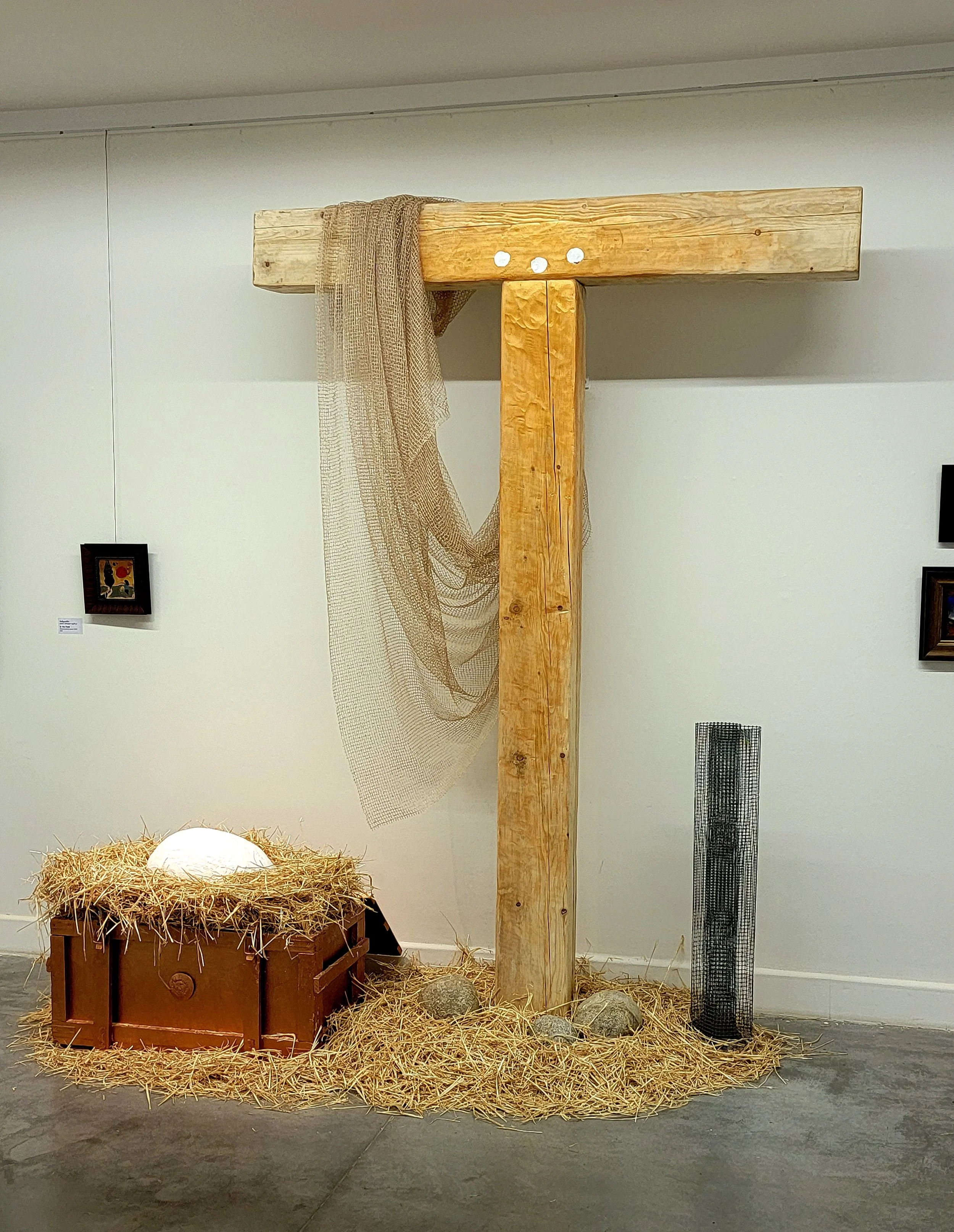 Anton Balanchivadze , Installation, Object, a large wooden cross with a draped piece of fabric, a manger with hay and a white object, and a metal cylinder with a grid pattern, set up as a nativity scene in Georgian National Gallery 