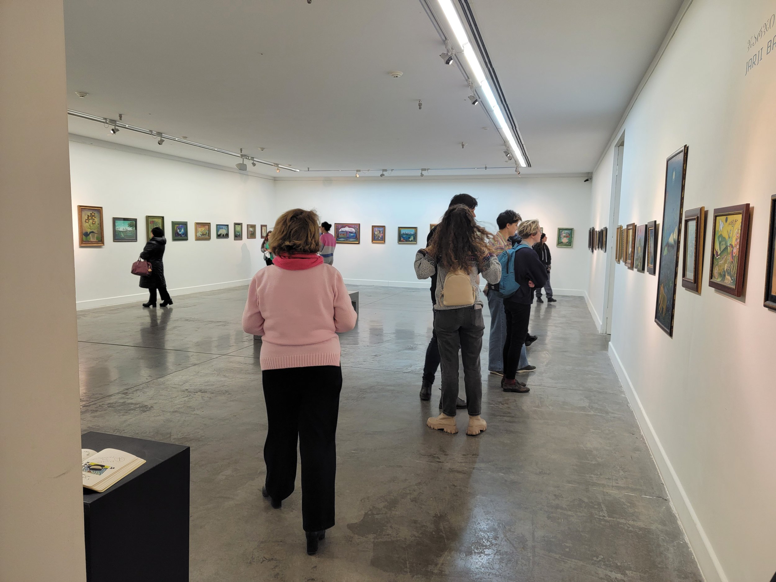 People viewing artwork in an art gallery with white walls and gray polished concrete floors.