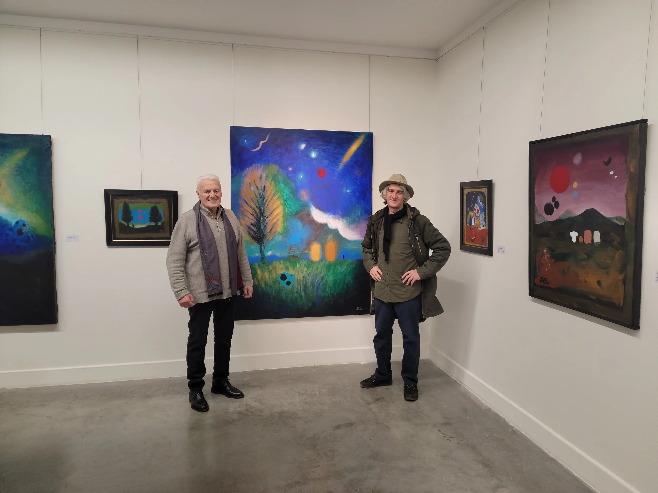 Anton Balanchivadze and Muraz Murvanidze in an art gallery with colorful paintings on white walls behind them.